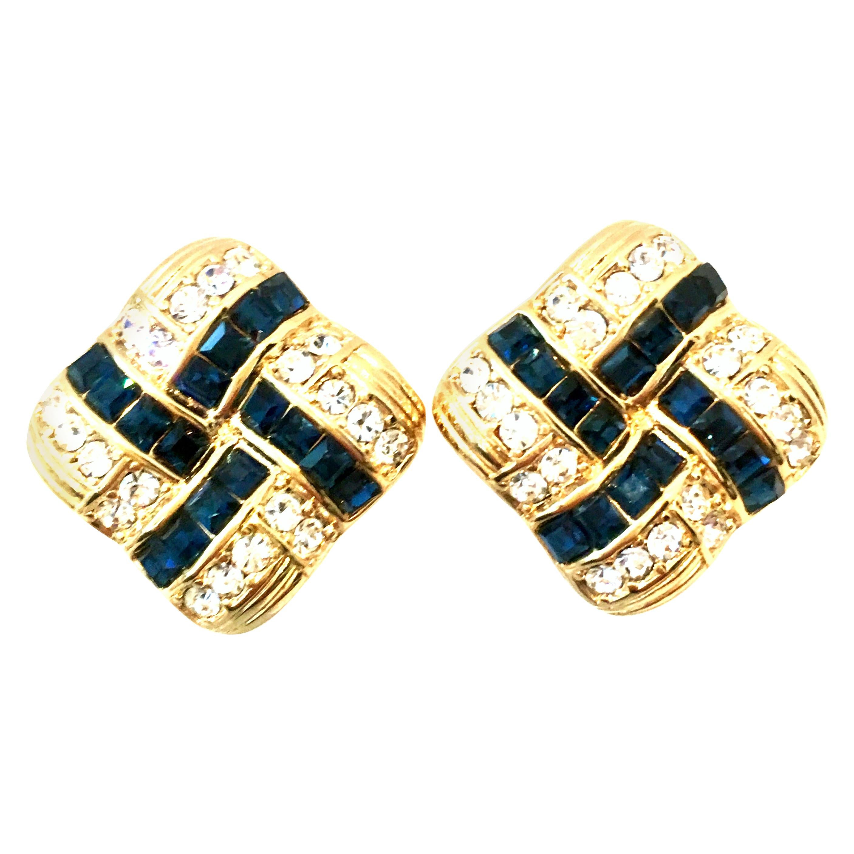 20th Century Pair Of Gold Plate & Swarovski Crystal Earrings By, Nolan Miller. These finely crafted Art Deco style dimensional and pillowed clip on earrings feature gold plate set brilliant cut and faceted Swarovski crystal sapphire blue and
