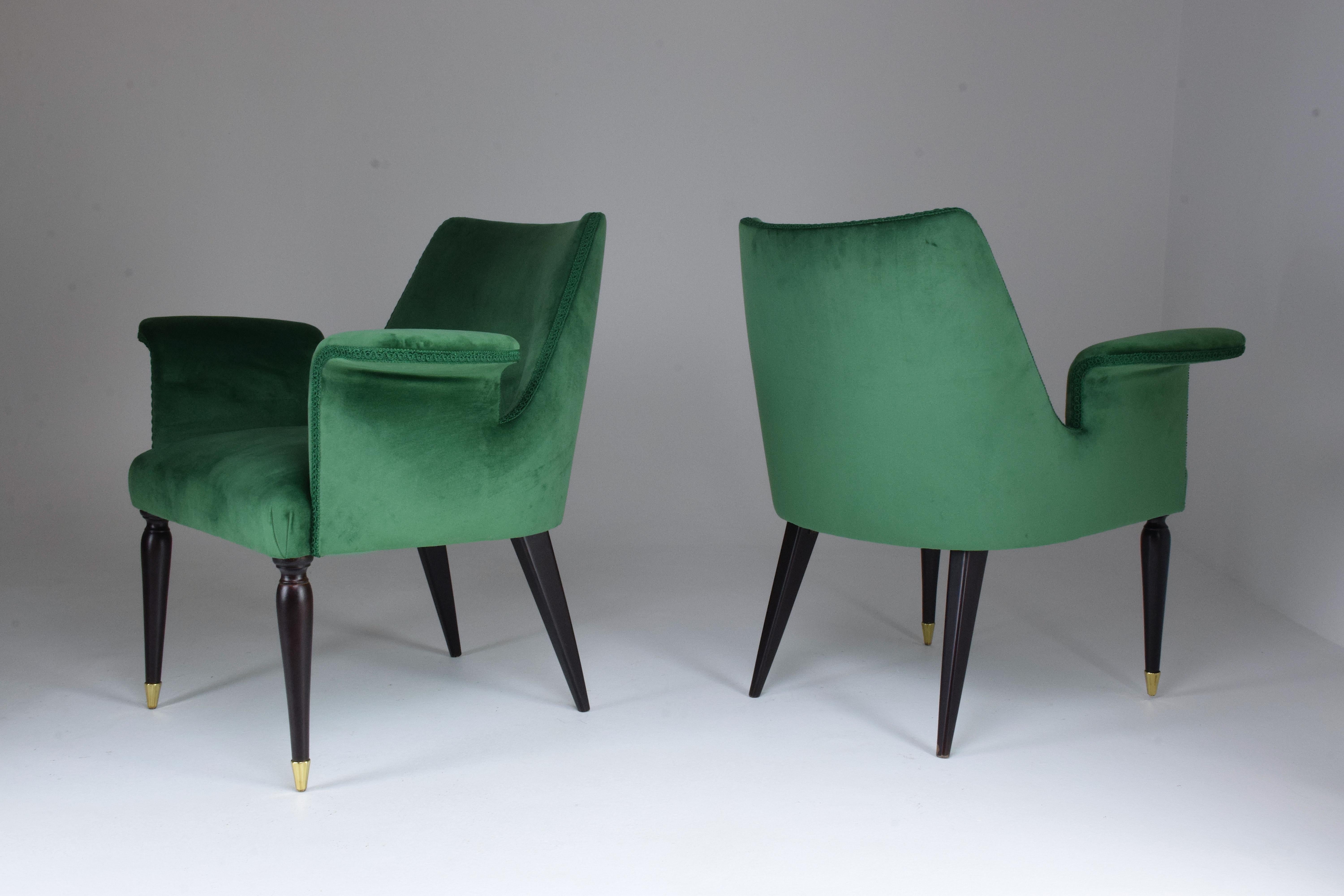 A set of two midcentury armchairs, circa 1940s. These have been expertly restored, through new finish and re-upholstered in a deep green velvet with new padding and beautiful upholstery trimmings.
The legs a tapered and splayed with a classic twist