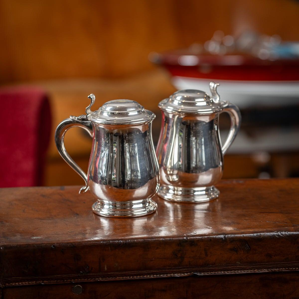 Antique 20th Century pair of Italian solid silver lidded tankards, the domed lid is applied with a cast thumb-piece, the scrolled handle terminating in a smooth point. The tankard features a bellied body on a flared foot, the sides are smooth. On