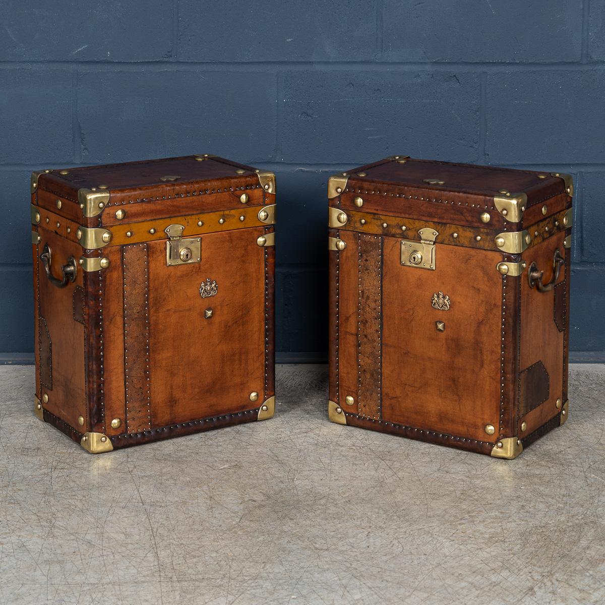 A pair of leather-clad Army and Navy style trunks, crafted in England in the late 20th century, they exude rugged sophistication and timeless appeal. Inspired by traditional military campaign trunks, they feature sturdy leather exteriors with robust