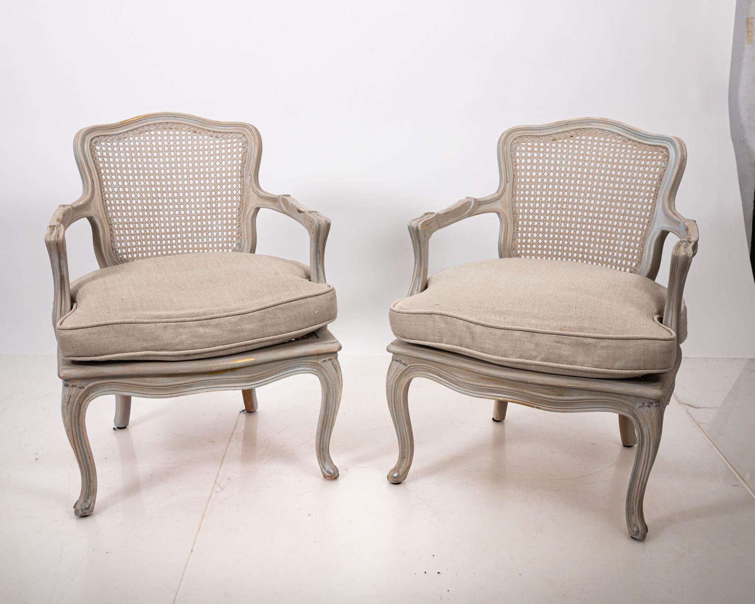 Pair of Louis XV style painted white/grey cane back armchairs with slight gold accent, circa 1960s. The chairs are also newly upholstered with either linen or cotton fabric down cushion. Please note of wear consistent with age. Made in France.