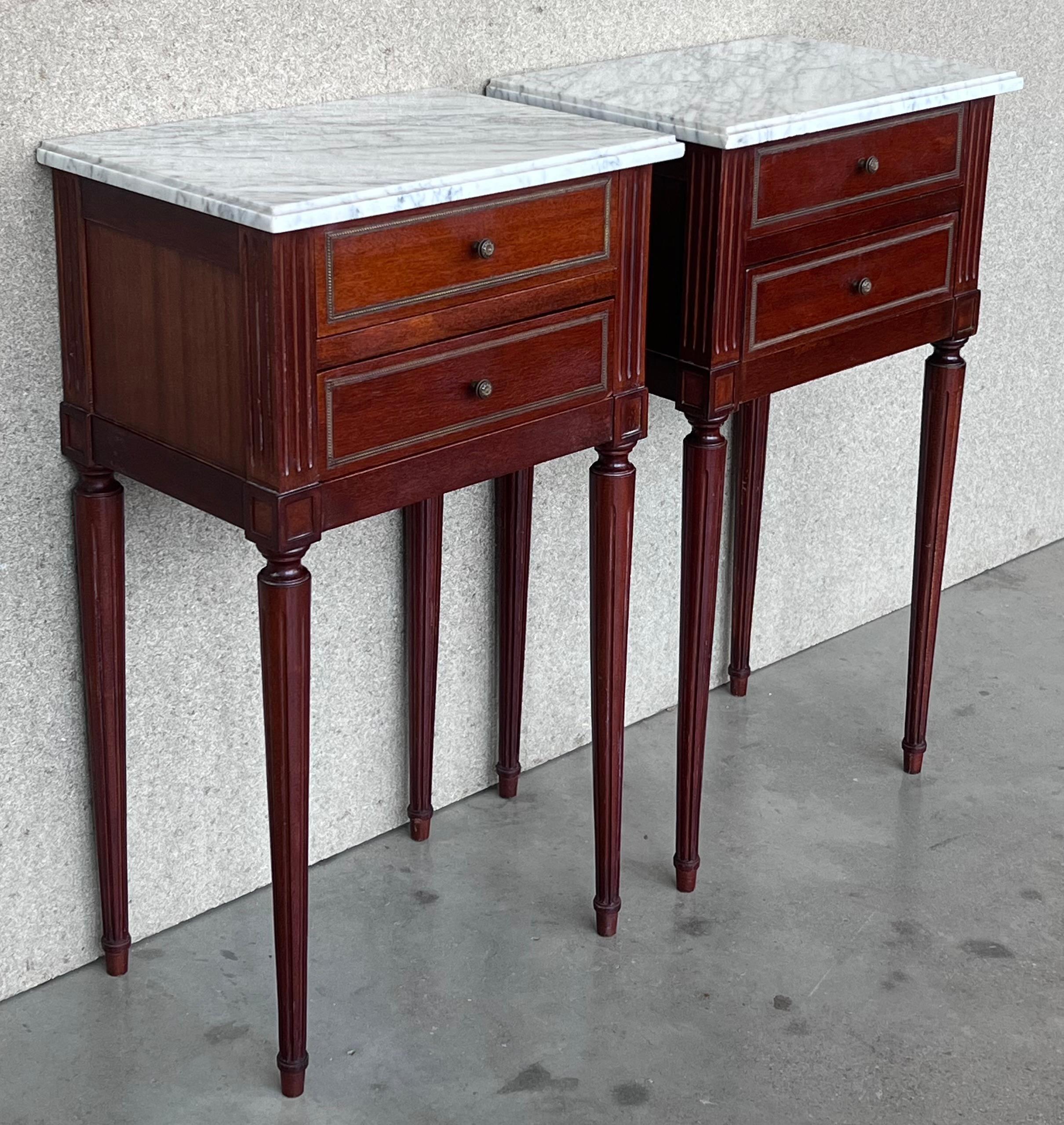 Antique French Louis XVI style pair of nightstands topped with a white marble, fluted legs. Two dovetailed small drawers with brass details in pulls.