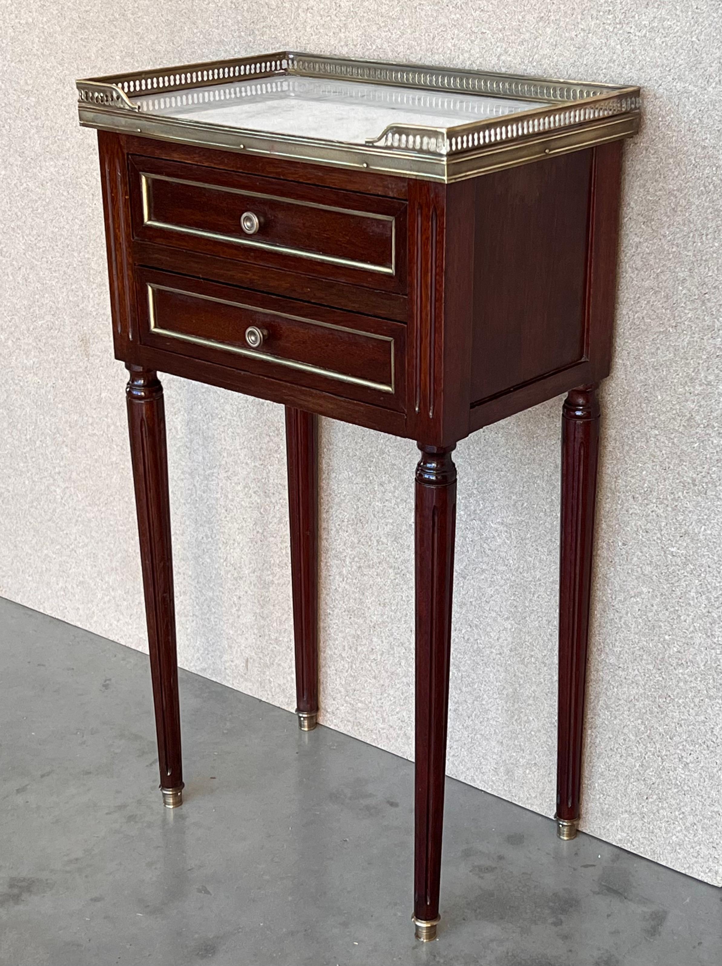 Antique French Louis XVI style pair of nightstands topped with a white marble, fluted legs finished with golden bronze clogs. Two dovetailed small drawers with brass details.