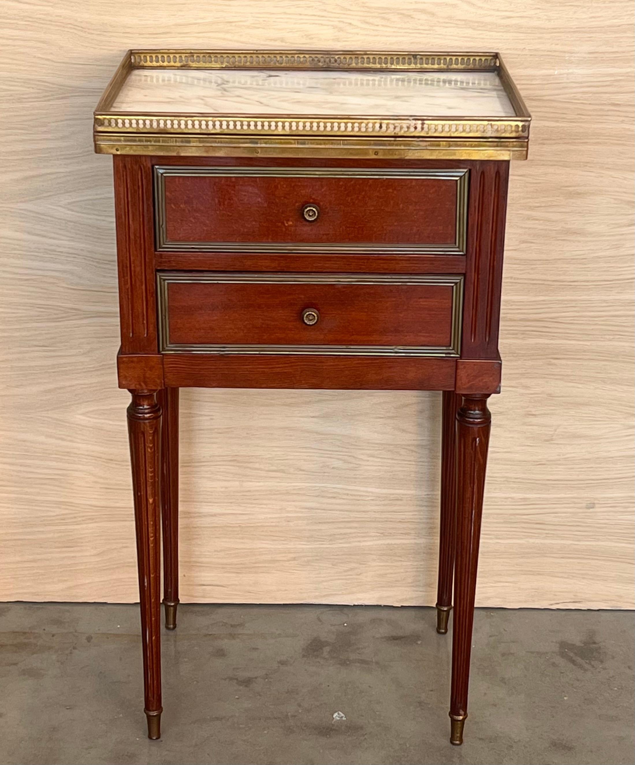 Antique French Louis XVI style pair of nightstands topped with a white marble, fluted legs finished with golden bronze clogs. Two dovetailed small drawers with brass details.
