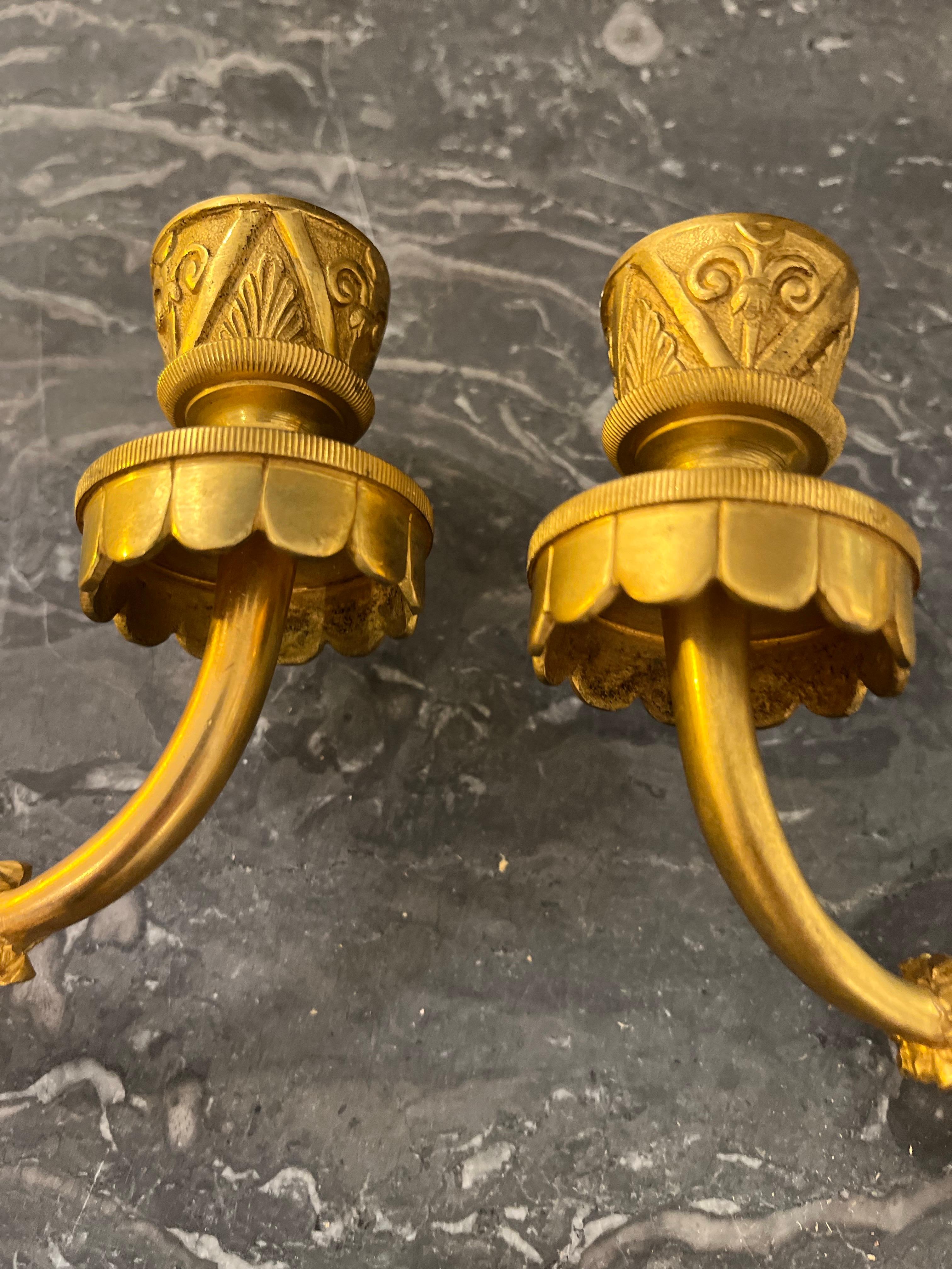 Ein wunderschönes Paar Kerzen-Wandleuchter aus dem französischen Maison Bagues. Jede Leuchte besteht aus einer rautenförmigen Platte, auf der zwei turbanförmige Köpfe aus lackiertem Messing ruhen. Von diesen Leuchtern gehen zwei Arme aus, die Kerzen