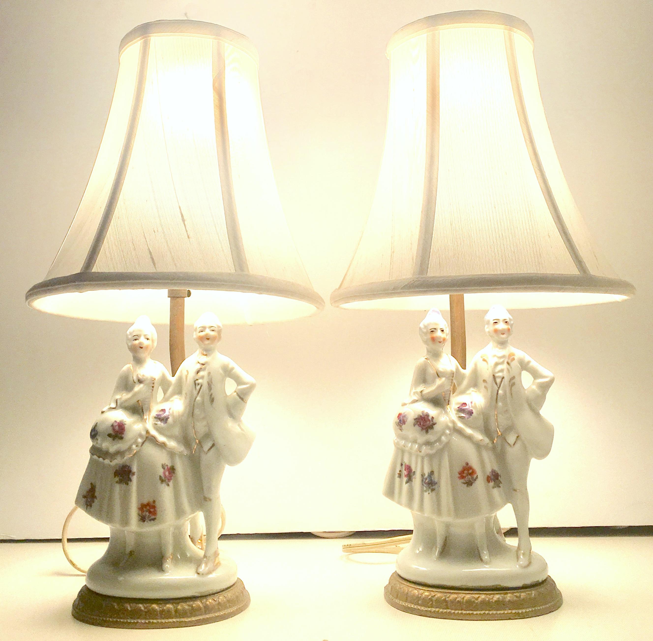 Antique  pair of Meissen style hand painted 22-karat gold porcelain and gilt bronze Identical courting couple boudoir table lamps. This rare pair of identical courting couple lamps are executed with a bright white ground, 22-karat gold, blue, pink,