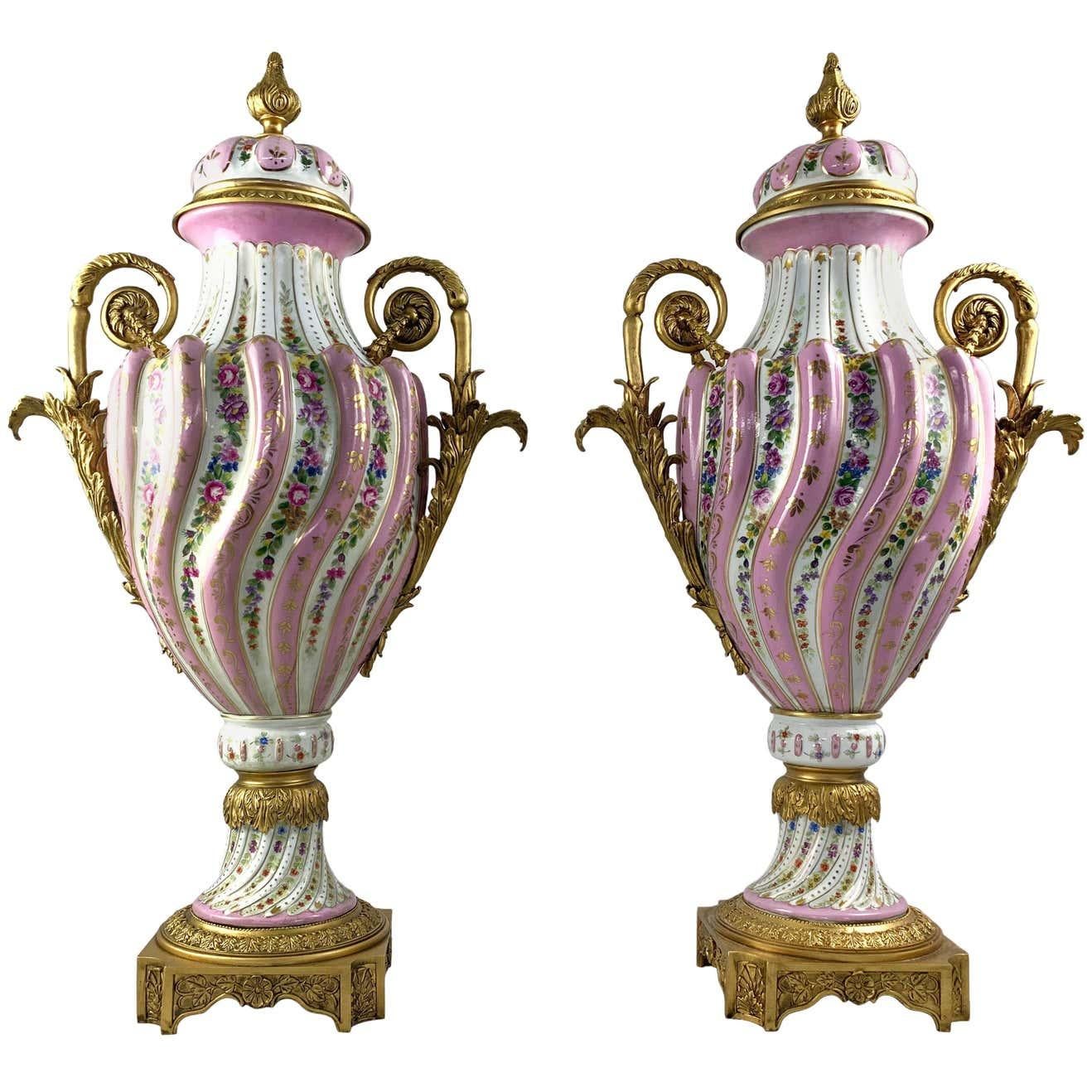 A fine pair of Sevres styleporcelain two handled vases and covers with ormolu mounts. 19th century. Each with spiral lobed decoration picked out with flowers on a pink ground. The mounts cast with classical motifs. Supported on a shaped square base.