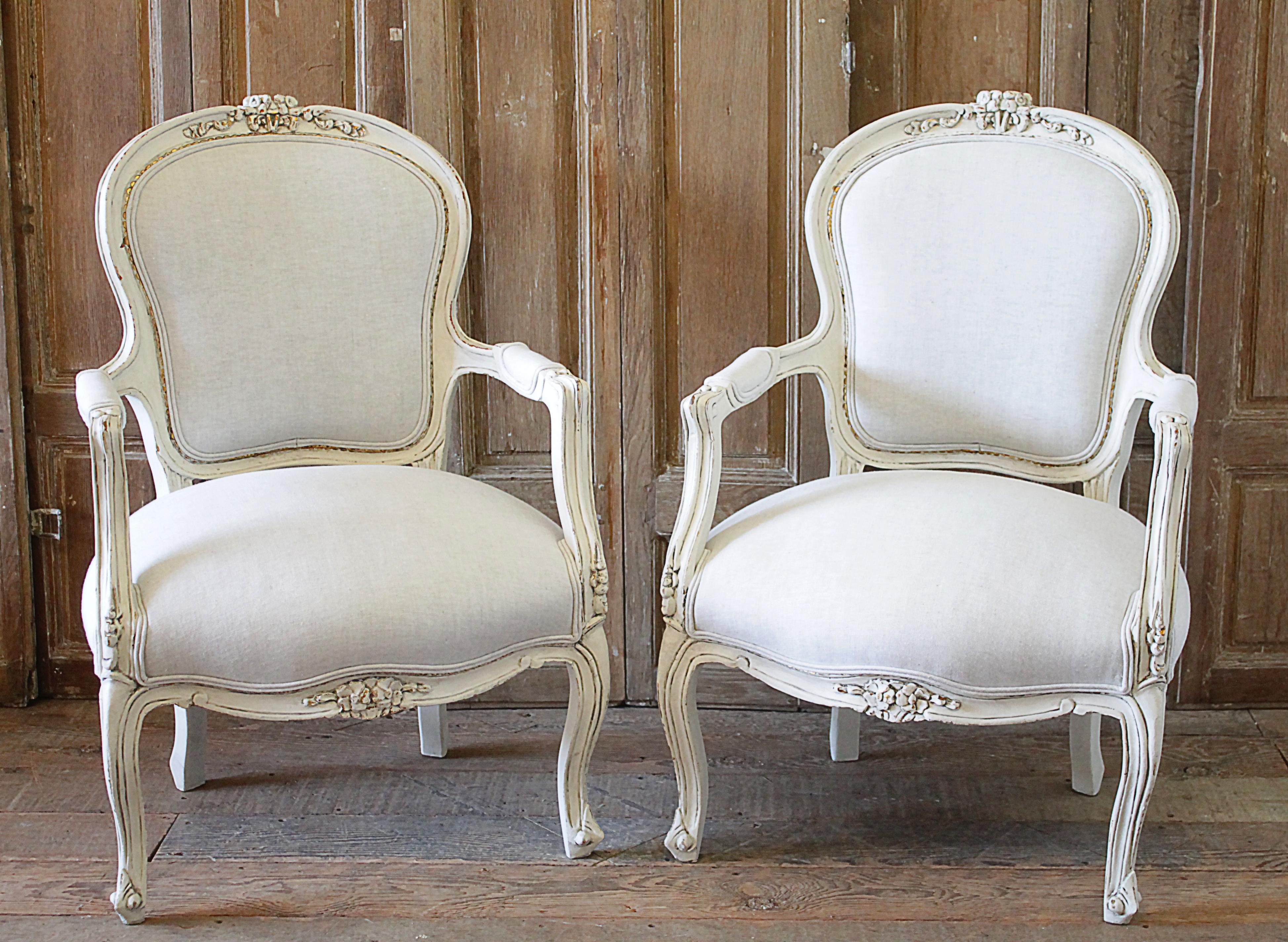 20th century pair of painted and upholstered Louis XV style open armchairs. Beautiful pair of painted chairs in our oyster white finish, with subtle distressed edges, and finished with an antique glazed patina. Classic Louis XV style. Reupholstered