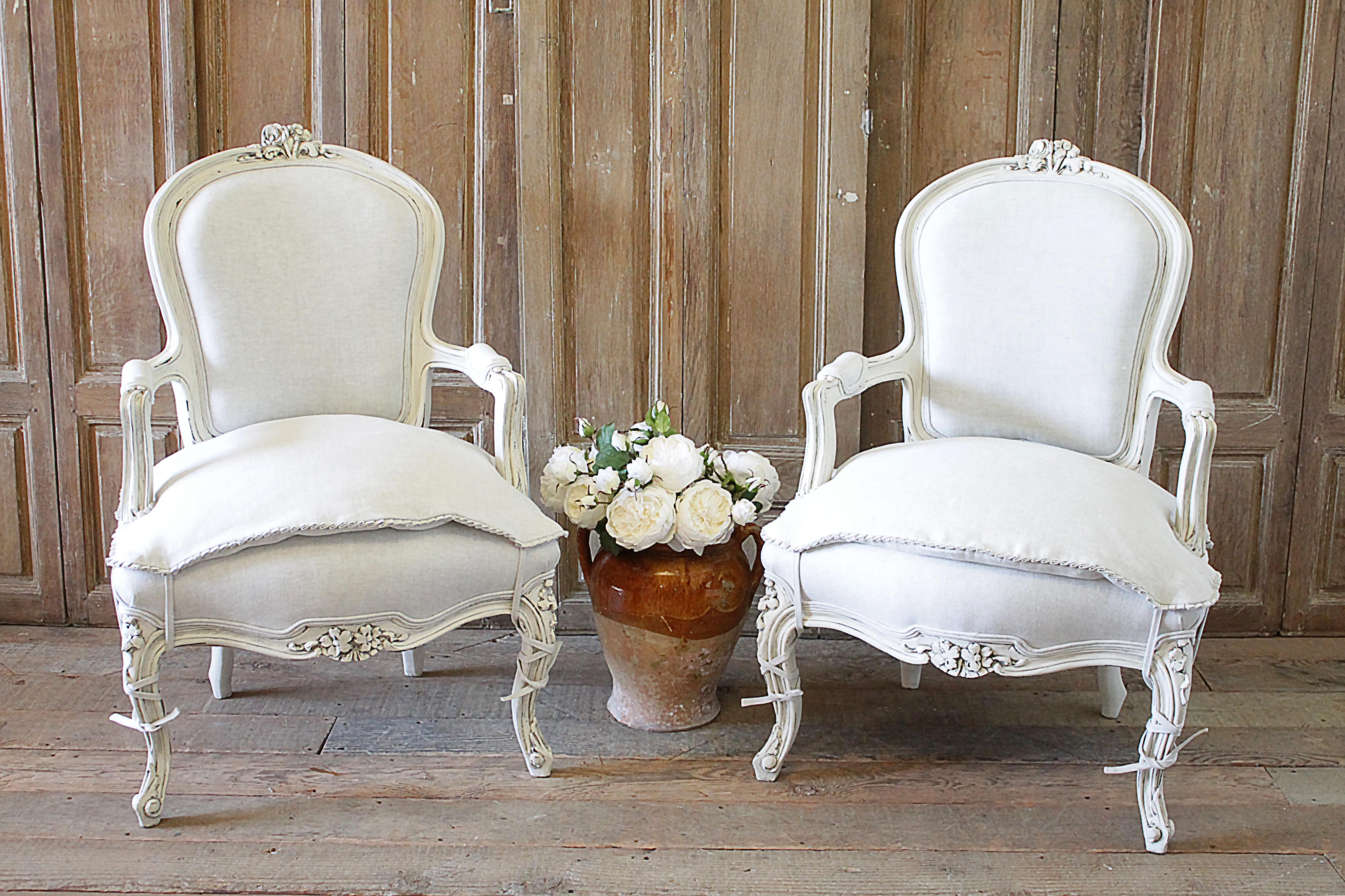 20th century pair of painted and upholstered Louis XV style open armchairs . Beautiful pair of painted chairs in our oyster white finish, with subtle distressed edges, and finished with an antique glazed patina. Classic Louis XV style. Reupholstered