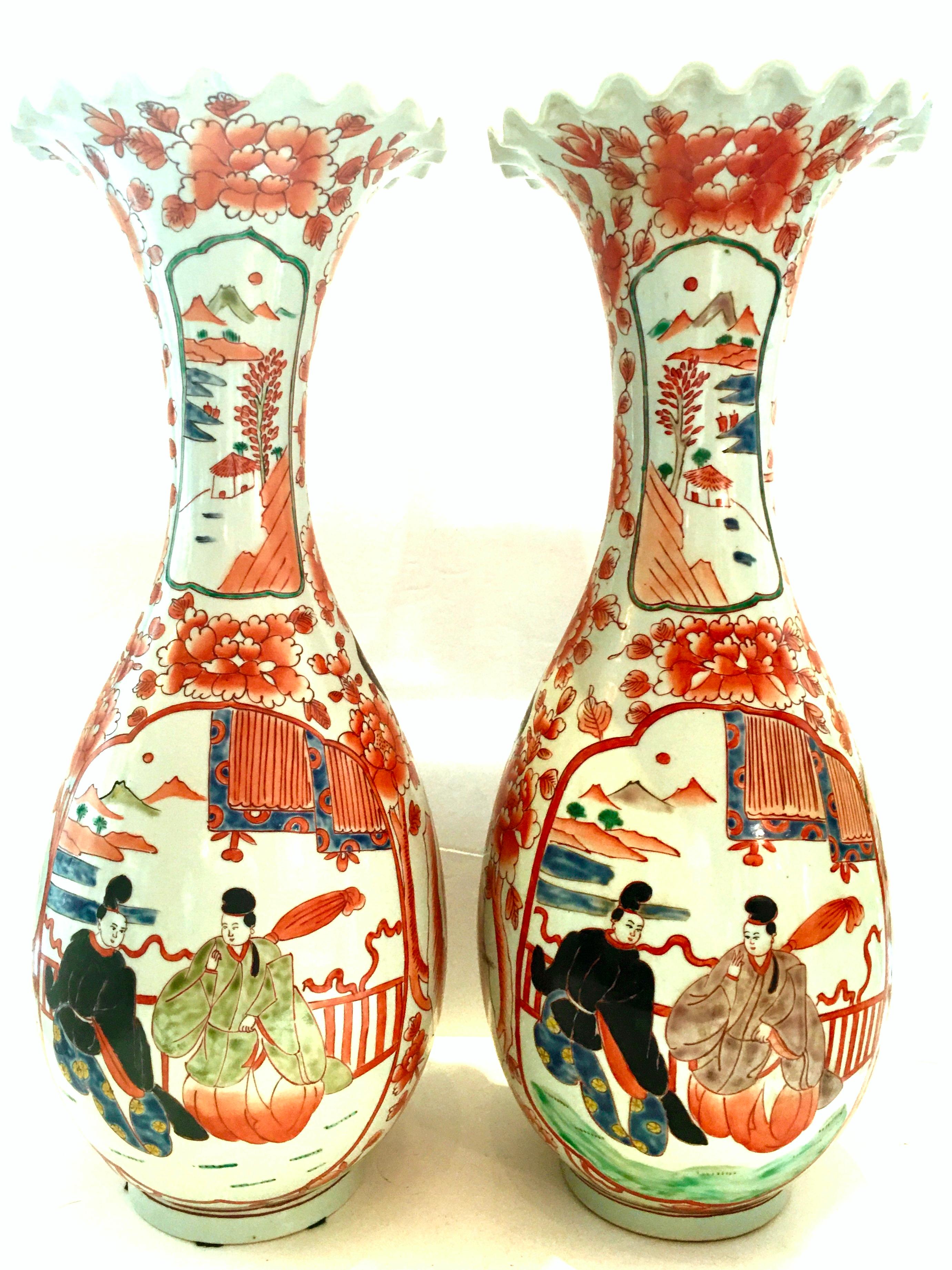 20th Century pair of tall Japanese Imari hand painted porcelain vases. These vases are double side portrait motif of a Japanese couple. Features a white ground, floral and peacock motif in coral, orange, black, blue, aqua and green. Flared