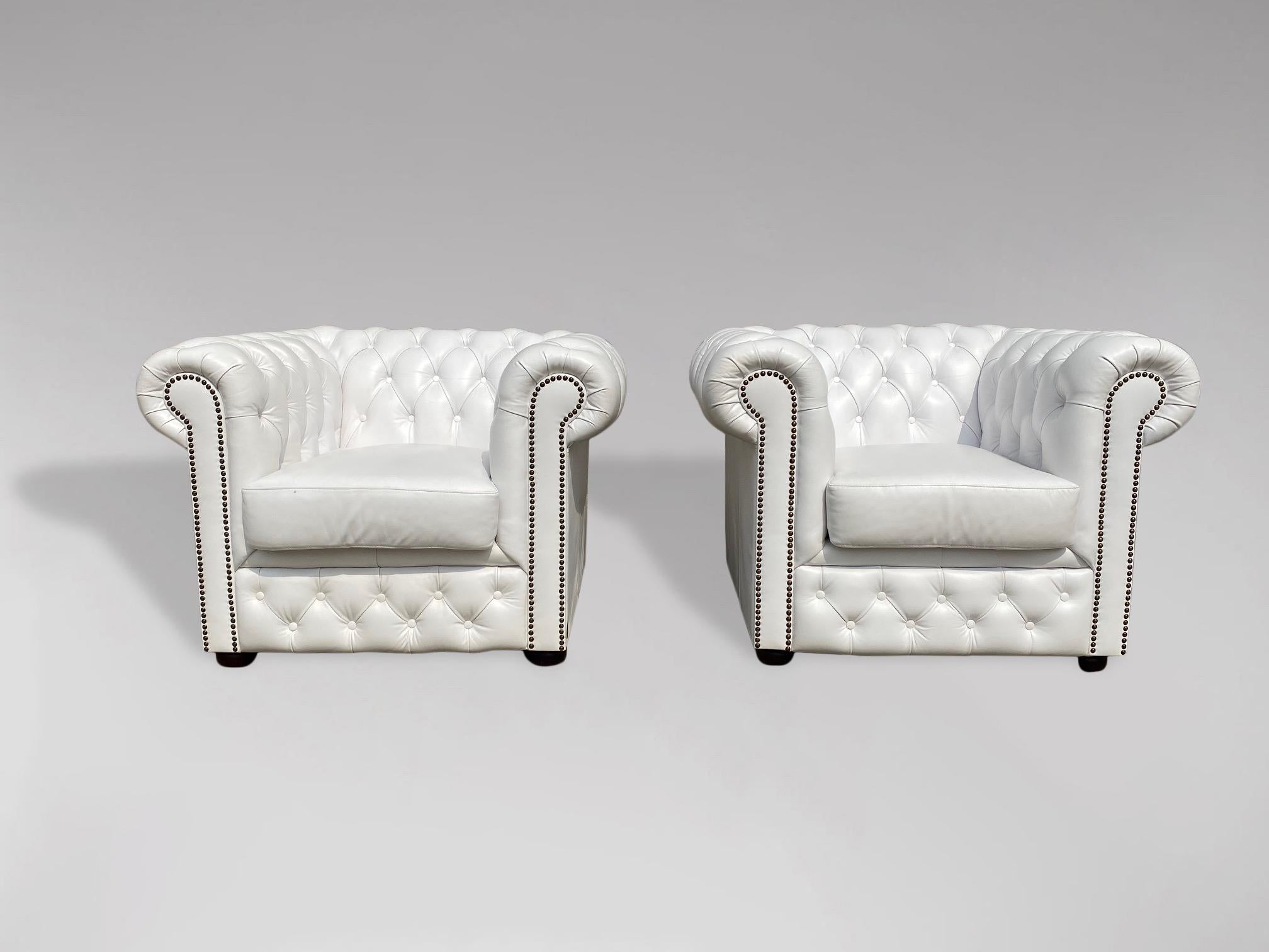 A pair of 20th century white leather chesterfield armchairs with a loose cushion, raised on 4 bun feet. A fine example of a pair of good quality comfortable chesterfield armchairs. Very comfortable seating. 

The dimensions are:
Height: 73cm