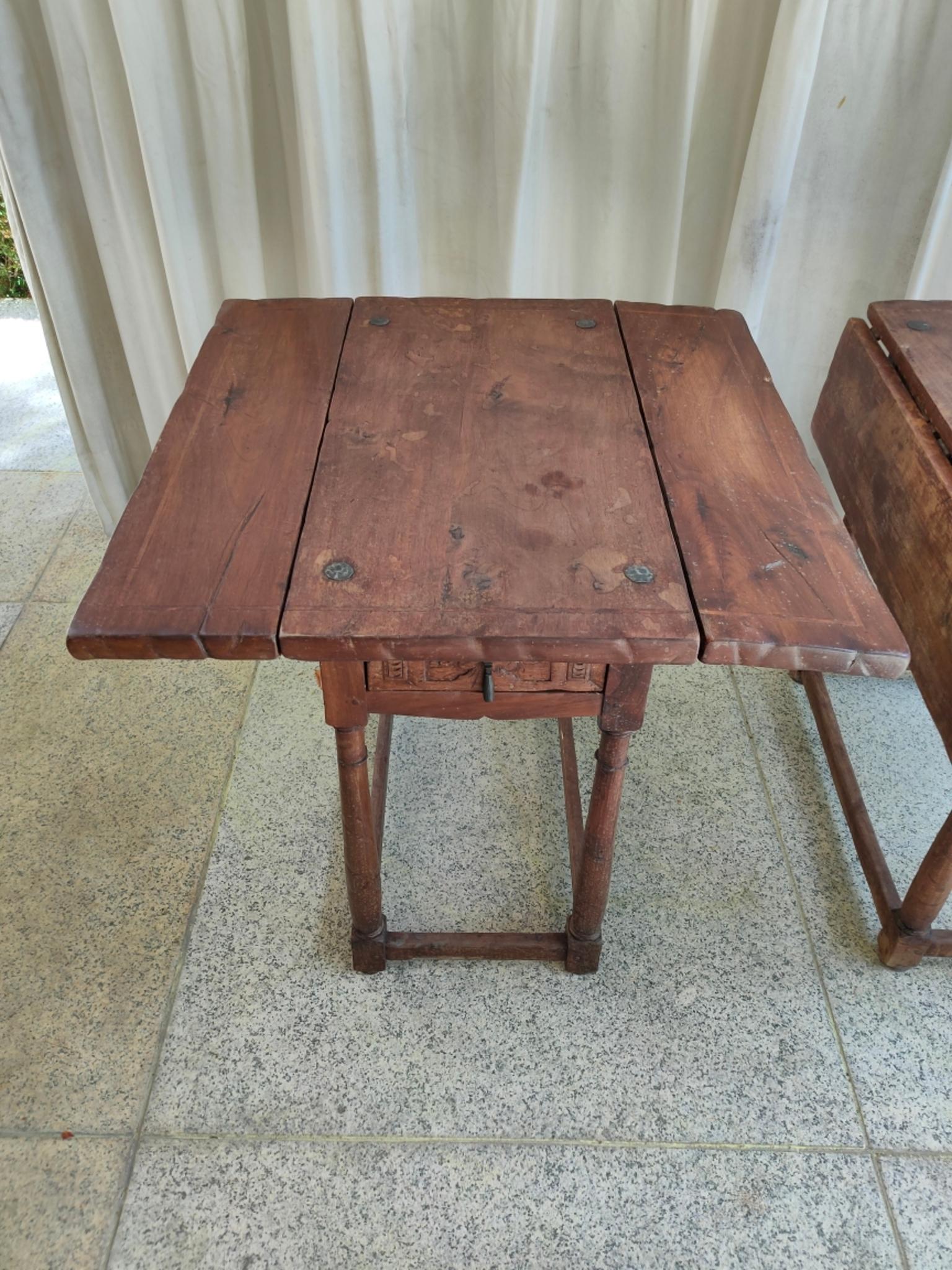 A pair of Spanish side tables, following baroque models, in walnut wood with turned legs and a drawer with an iron handle, the tables can be extended to both sides.