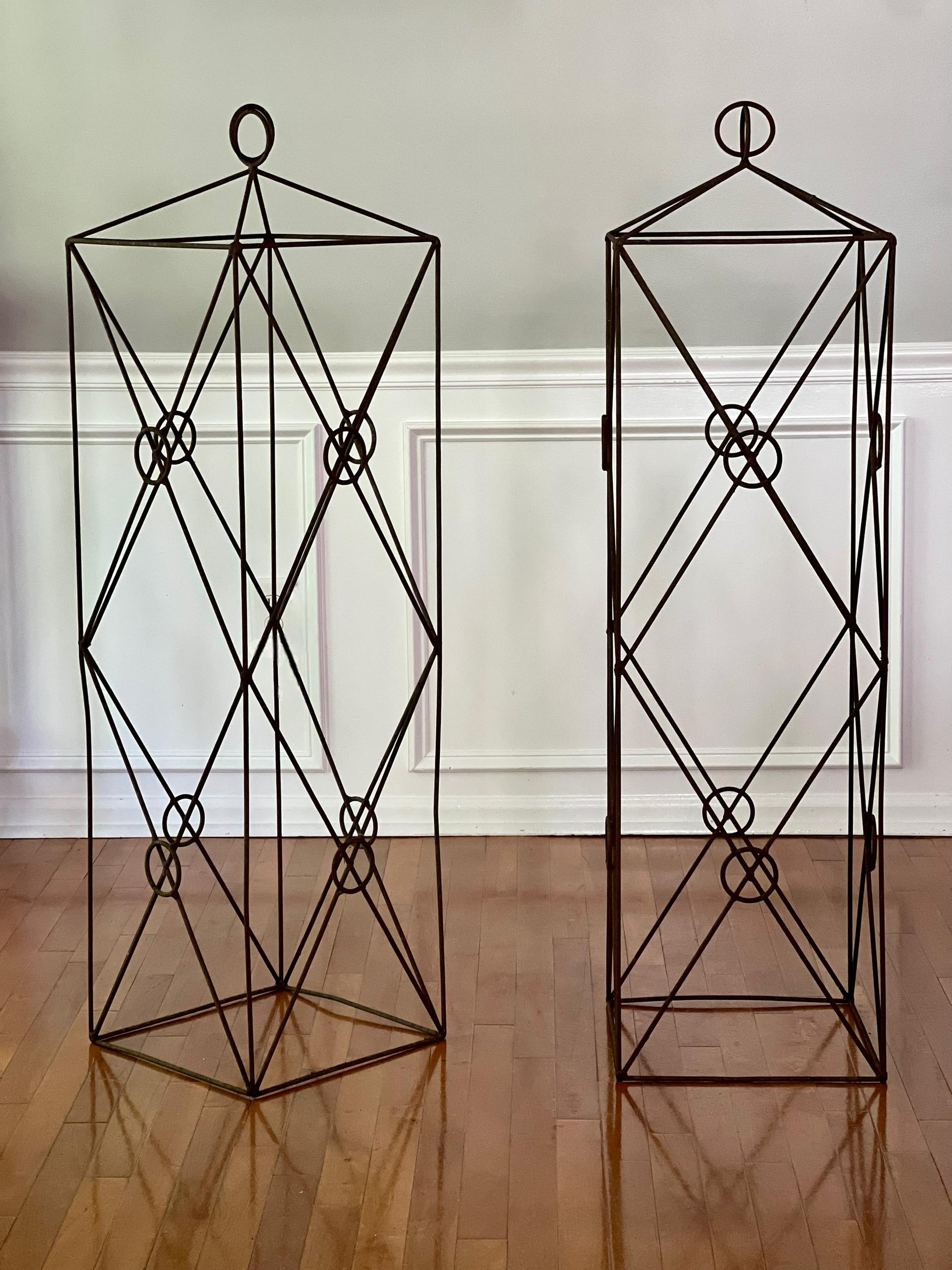 Pareja vintage de obeliscos o espalderas cuadradas de hierro forjado para jardín.  Elegante pareja con un diseño neoclásico atemporal de forma lineal con figuras geométricas, un cuerpo cuadrado sustancial y un remate de doble anillo entrelazado