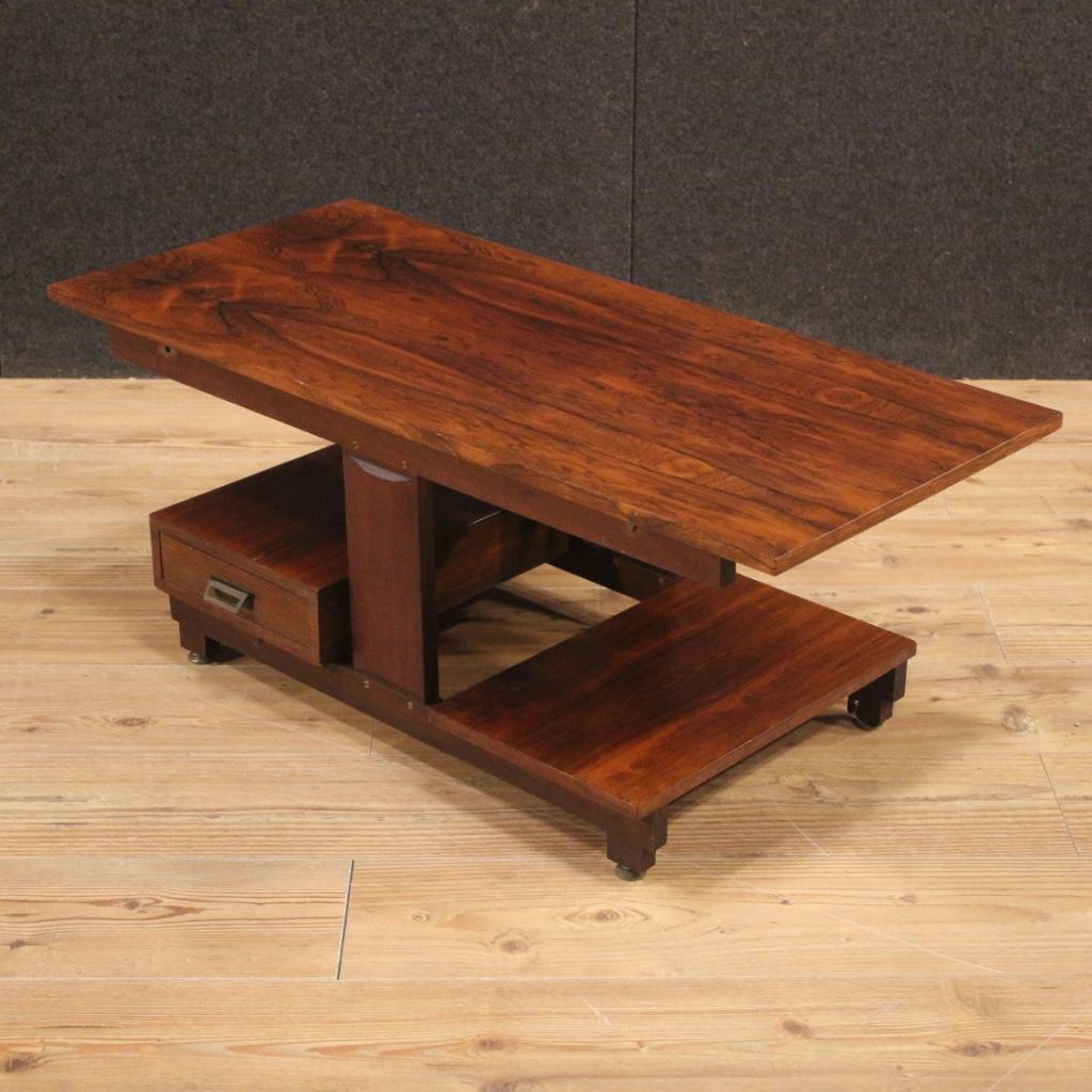 Italian design coffee table from the 1960s-1970s. Furniture veneered in palisander and mahogany with supporting elements in oak and beech. Coffee table with three support tops and a sliding drawer that can be opened from both sides (see photo).