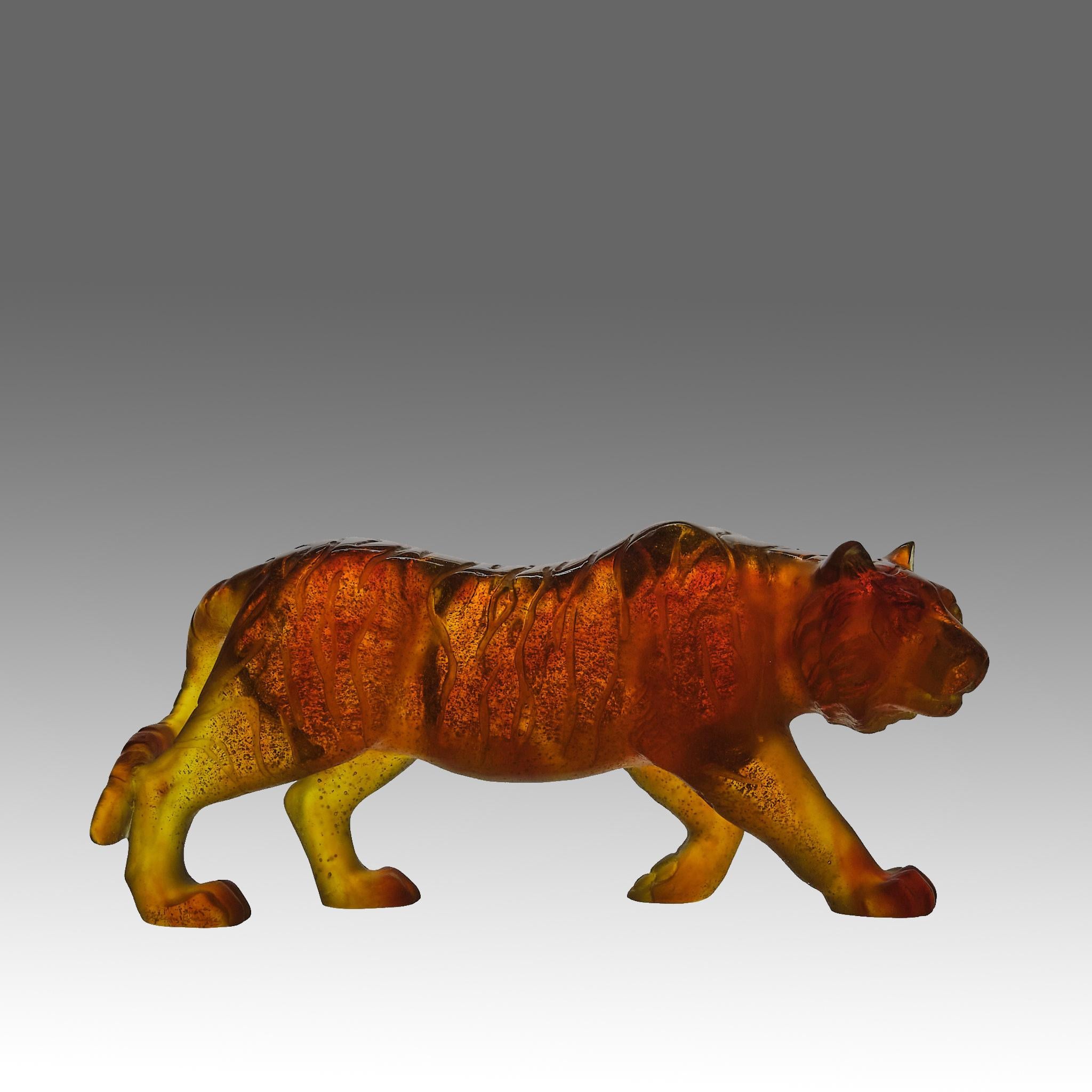 Eine außergewöhnliche französische Pâte-de-verre-Glasskulptur aus der Mitte des 20. Jahrhunderts, die einen umherstreifenden Tiger darstellt und in satten Bernsteintönen gehalten ist, die in durchscheinende Highlights übergehen. Das Stück zeichnet