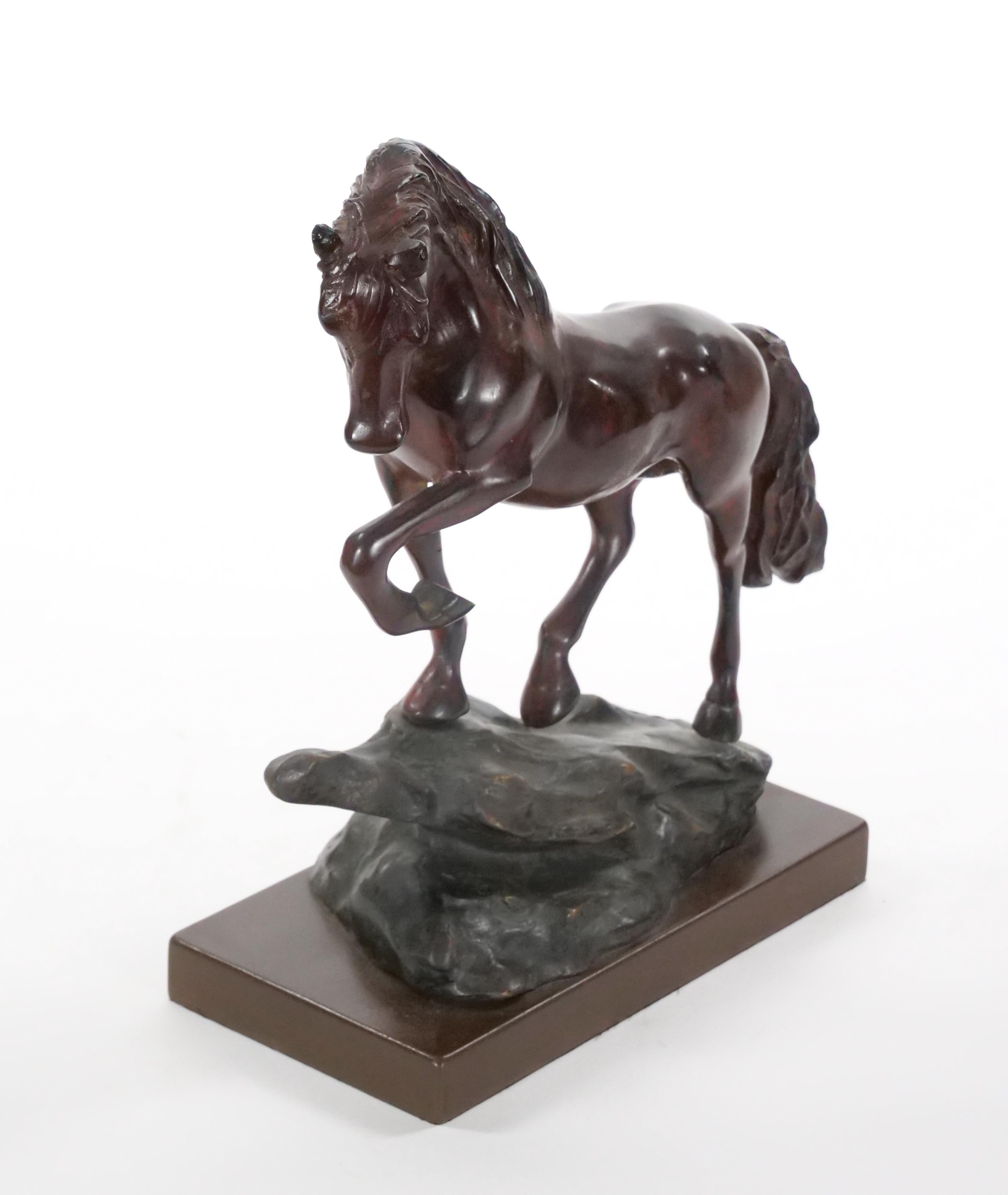 Cette étonnante sculpture en bronze patiné du XXe siècle capture l'élégance dynamique d'un cheval posé sur un rocher, un pied en l'air. Les détails plus vrais que nature et la finesse de l'exécution mettent en valeur la musculature puissante et la