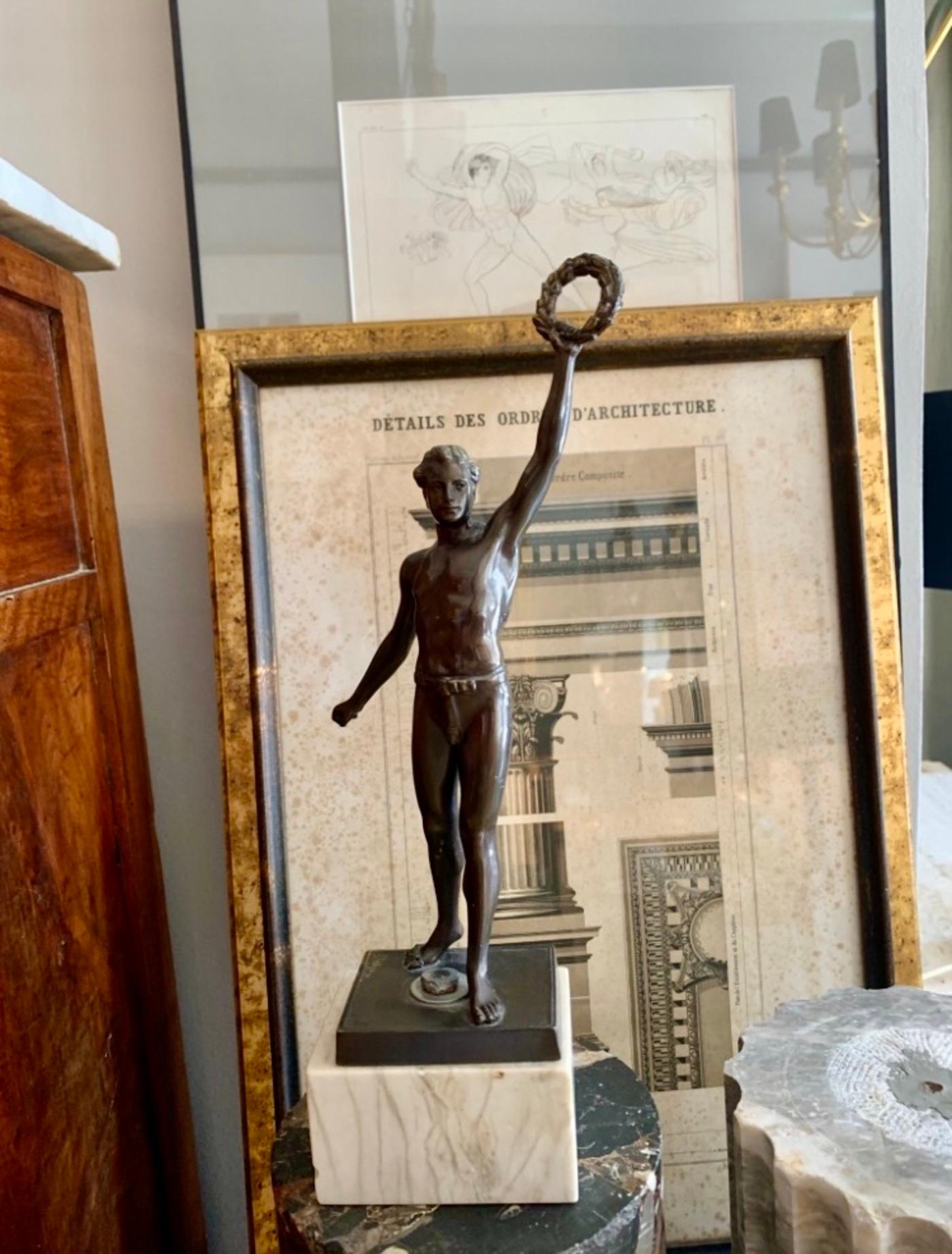 Sculpture from the first half of the 20th century in patinated metal that represents an athlete with a trophy in the form of a laurel wreath, with a marble base.
