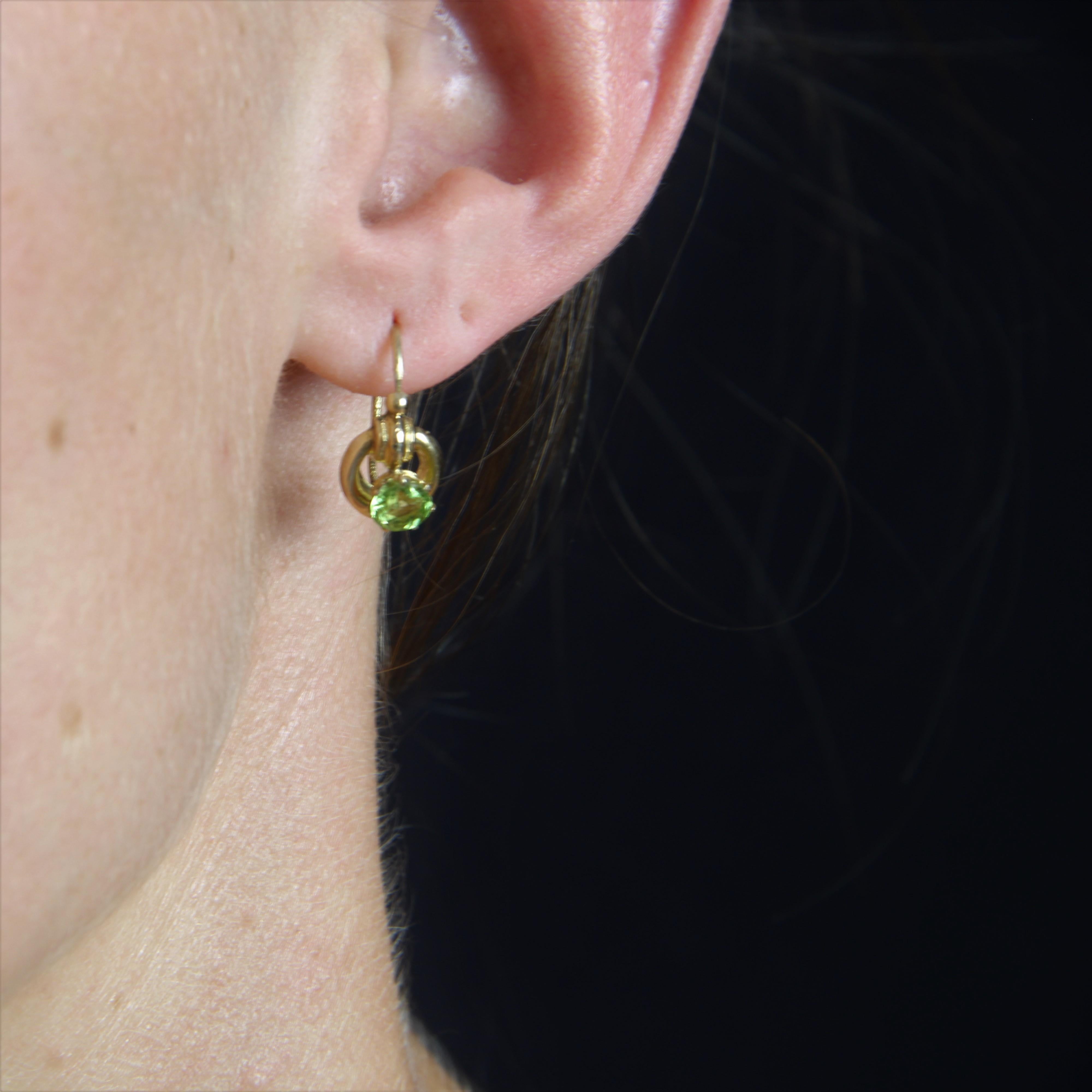 For pierced ears.
Earring in 18 karat yellow gold.
These sleeper earrings form a gold hoop topped with a gadroon decoration and a gold pearl. Each is set with a round peridot. The clasp threads through the back.
Total weight of peridots : 1,10 g