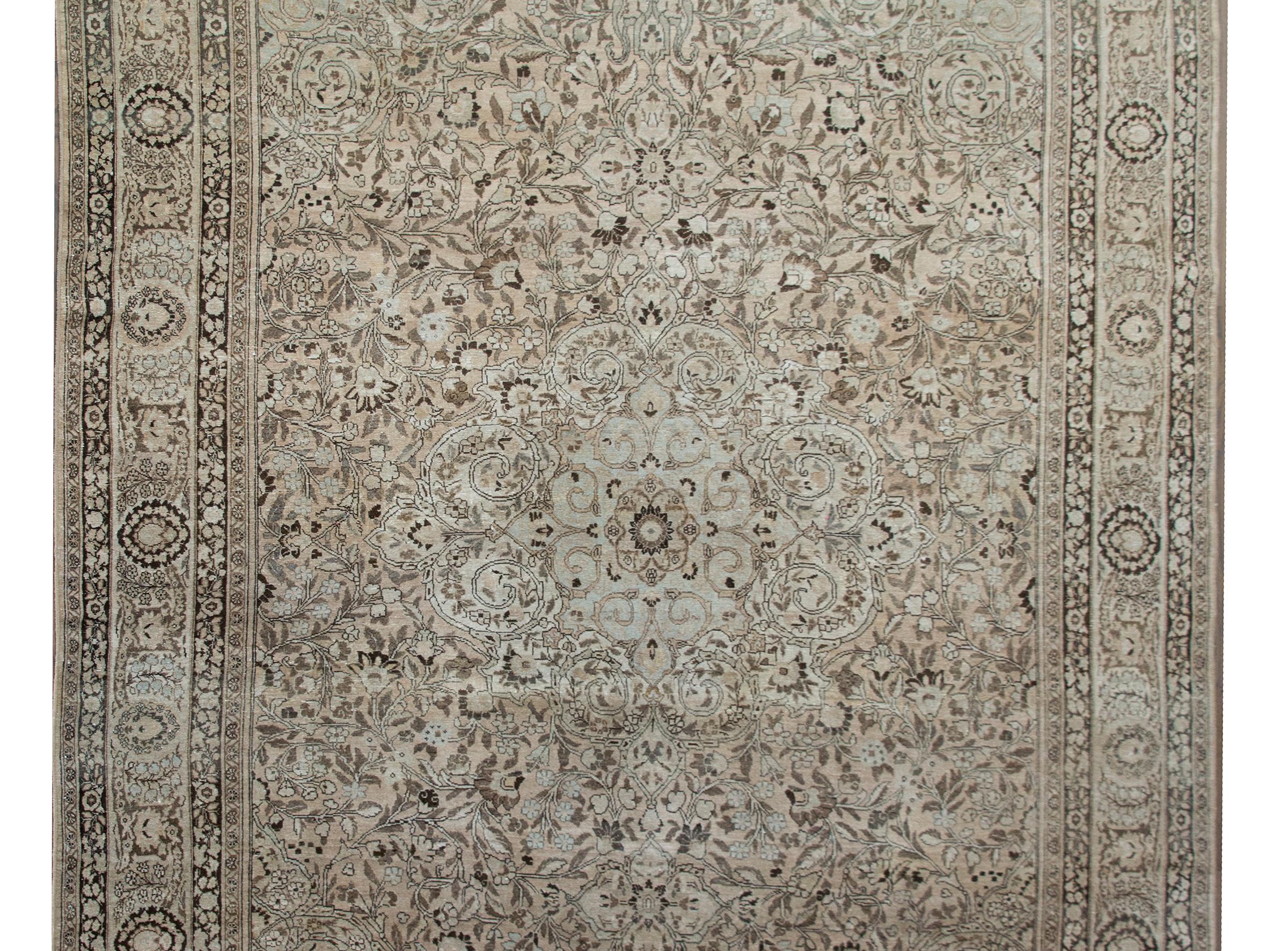 A chic Mid-20th Century Persian Tabriz rug with an all-over lacy floral and scrolling vine pattern surrounded by a complex border with more petite floral patterned stripes flanking a wide central floral stripe, and all woven in muted browns, grays,
