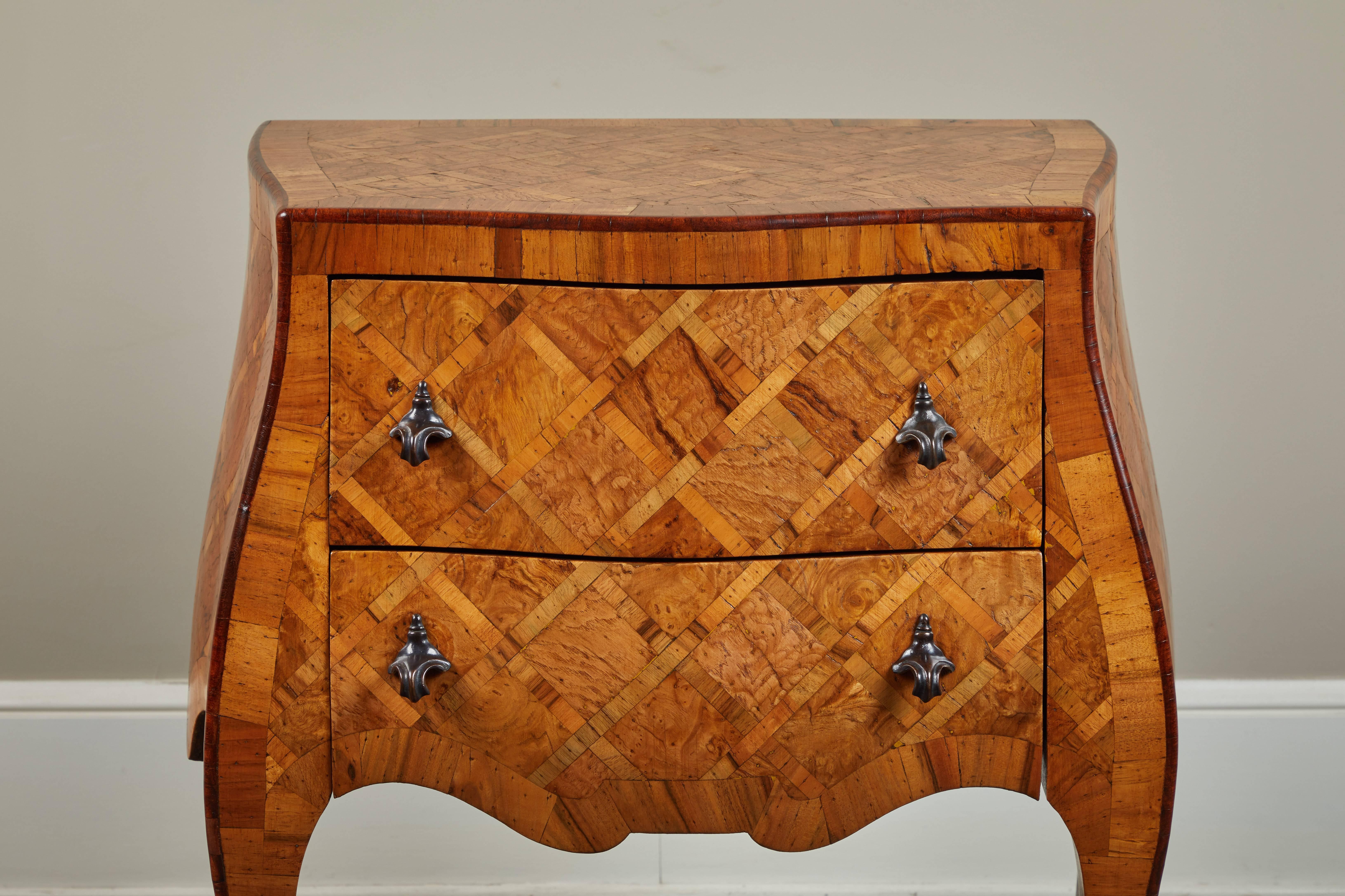 An early 20th century petite Italian marquetry chest of drawers. Gorgeous dark hardware on two drawers.