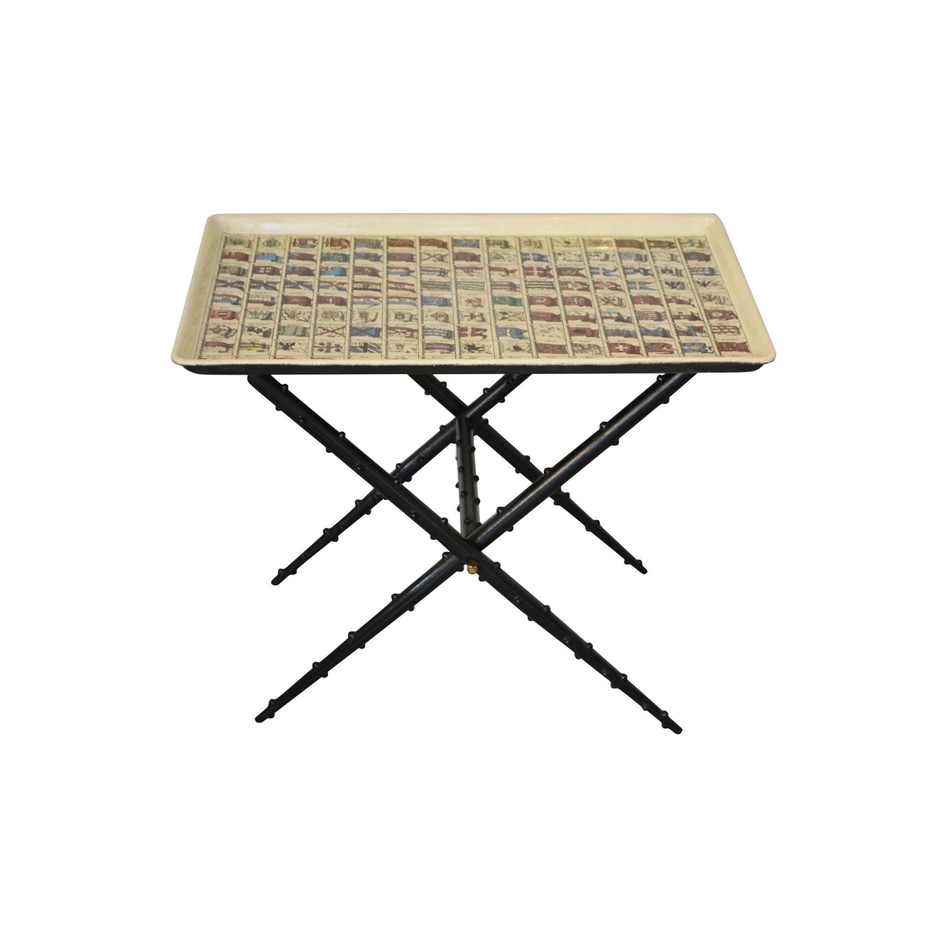 Low table with folding structure and removable tray with theme flags, designed by Piero Fornasetti in the 1960s. Structure in lacquered metal and tray in screen printed metal. There is the manufacturer's label and brand name under tray as shown in