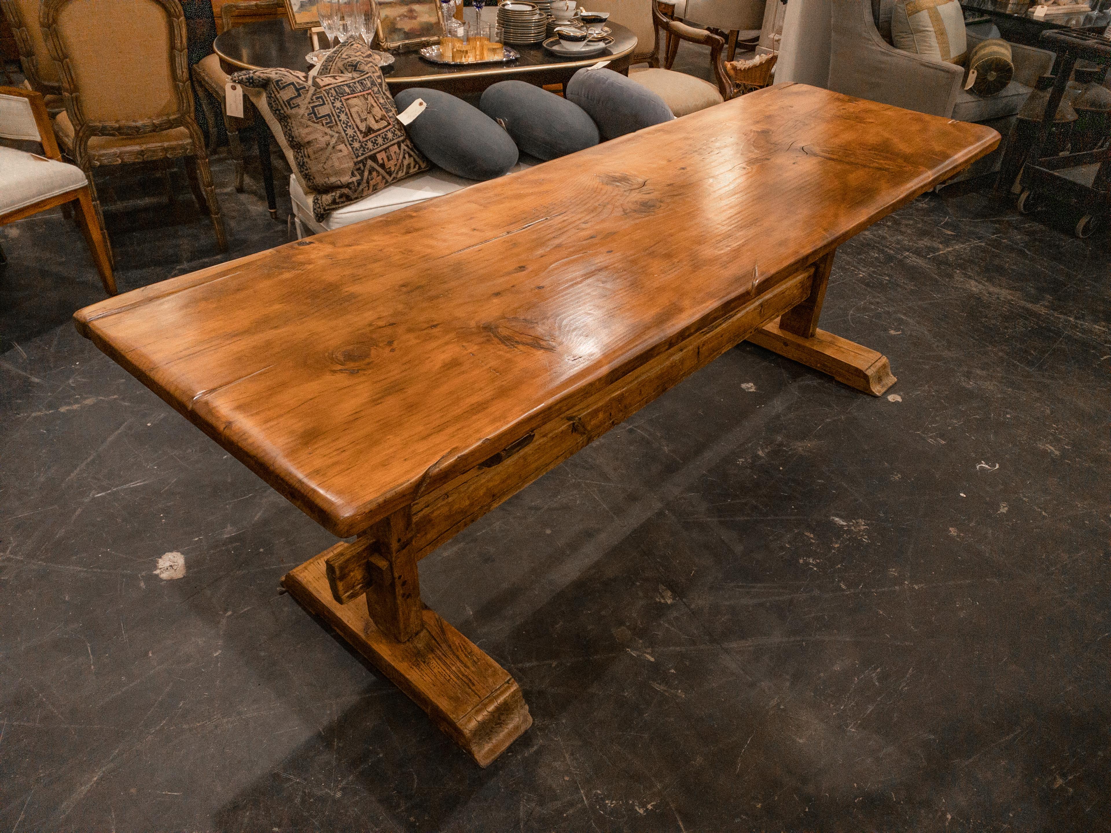 The 20th Century Pine Trestle Table epitomizes the rustic charm and functionality of its era. Crafted from solid pine, it boasts a sturdy trestle base that provides stability and durability. With its natural wood grain and warm finish, the table