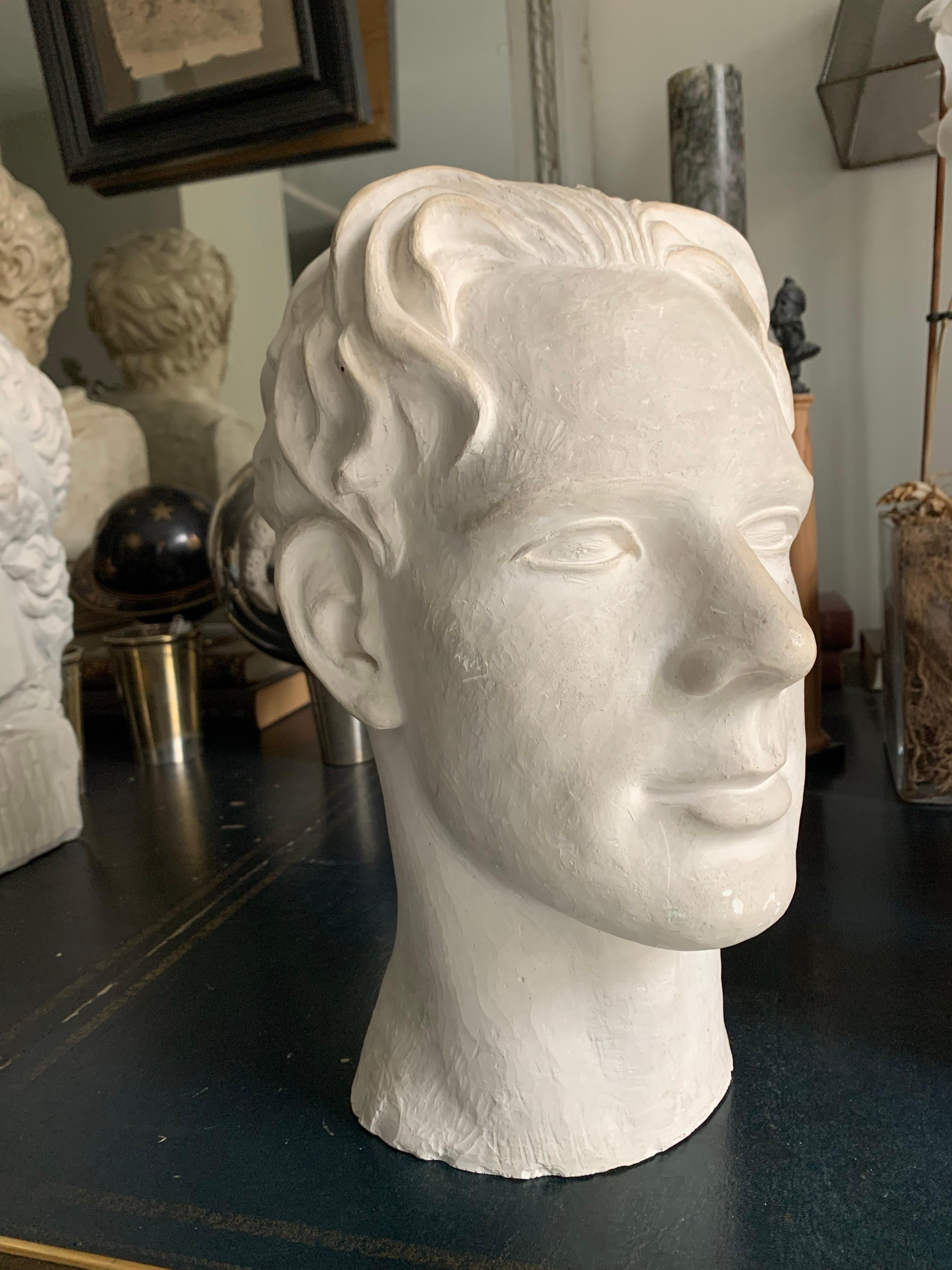 Un busto in gesso raffigurante un giovane uomo, firmato in basso da Stina Edman
