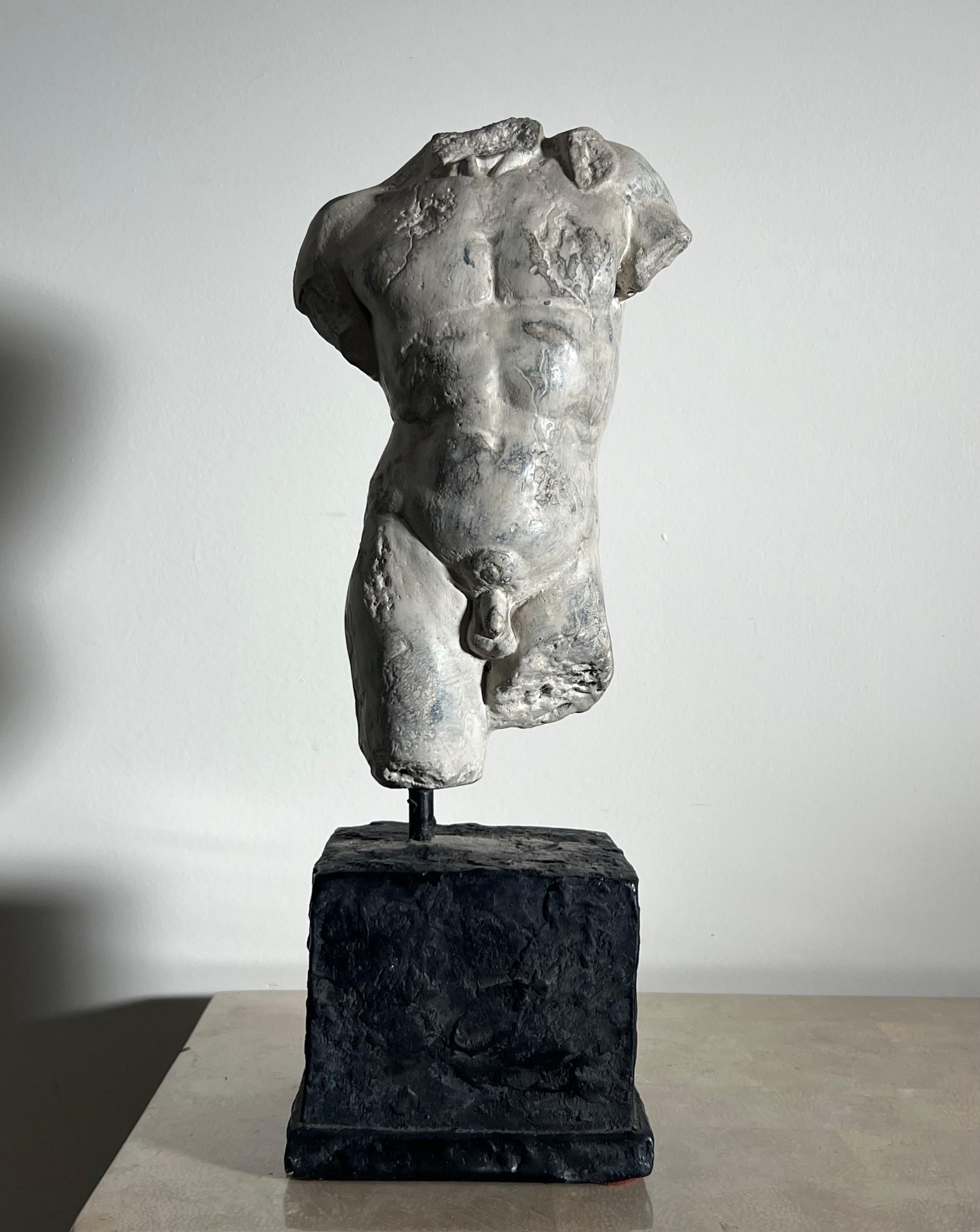 A statue of a nude male bust or torso, hand-carved of plaster, d’après Michelangelo or the Ancient Greek Hellenistic and Roman Imperial classics, late 20th century. Mounted on a plaster plinth. Dare I say rather well-endowed for the classics. No