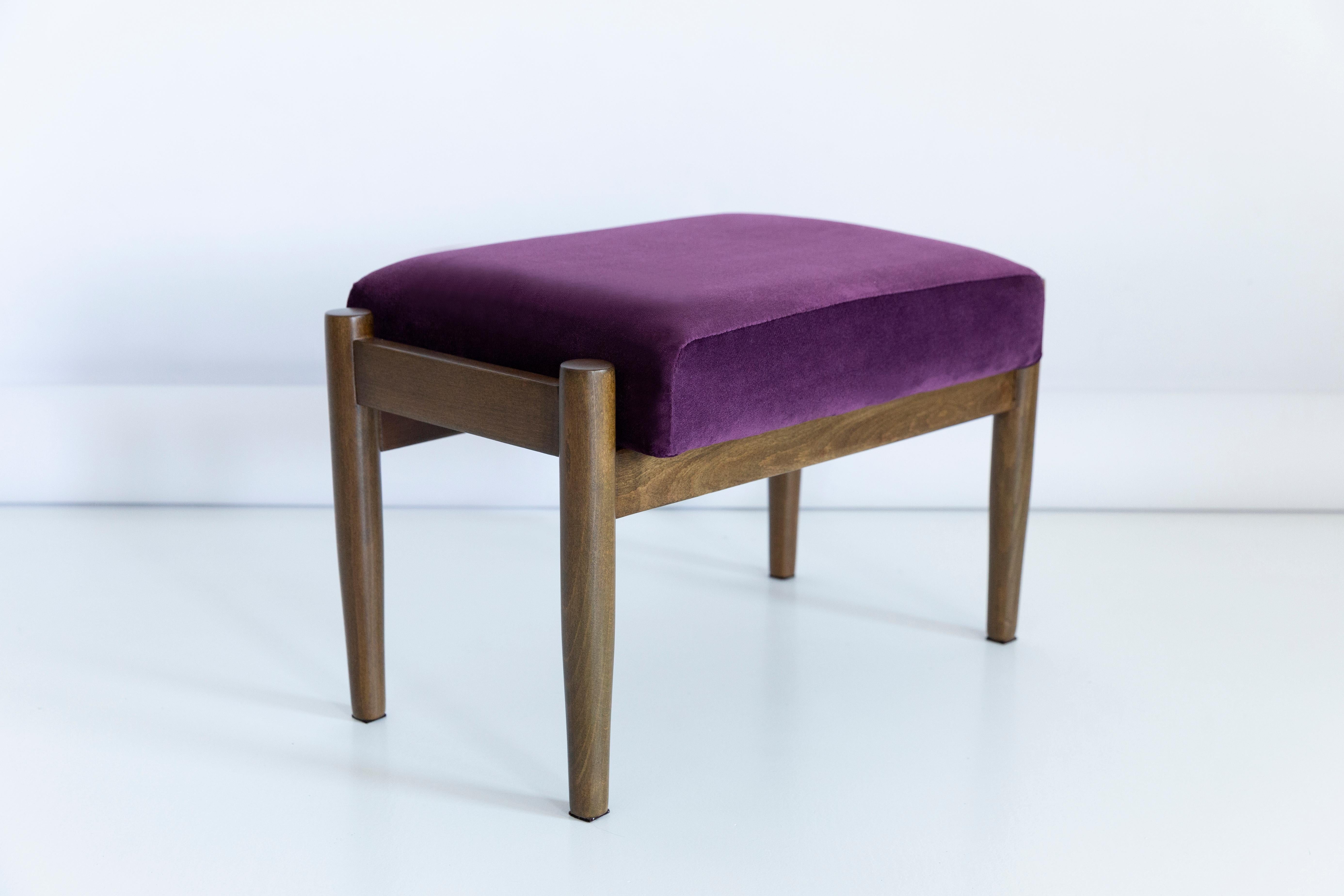 Tabouret du tournant des années 1960. Magnifique tapisserie en velours violet de haute qualité (couleur 969). Le tabouret est composé d'une partie rembourrée, d'un siège et de pieds en bois se rétrécissant vers le bas, caractéristiques du style des
