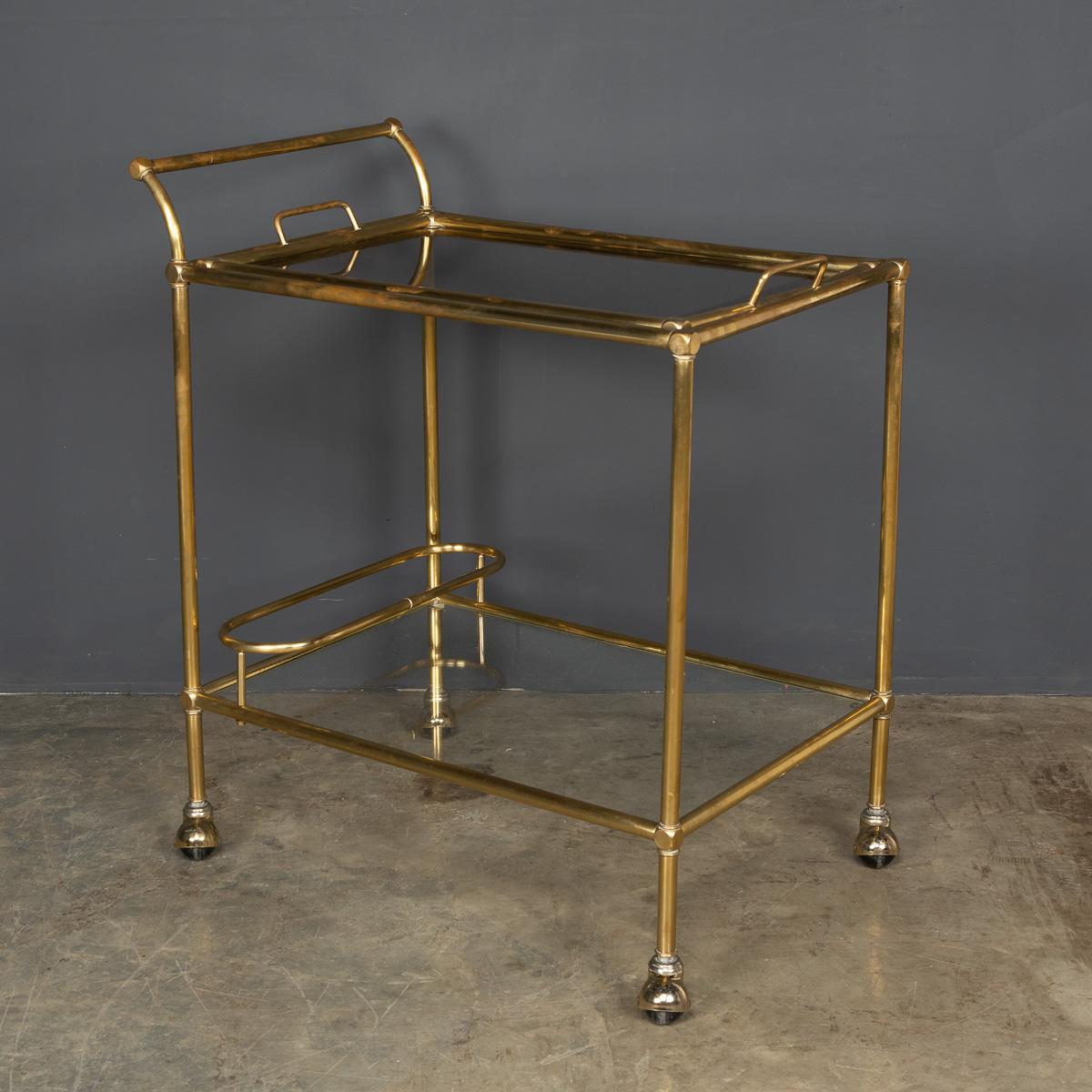 Stylish 20th Century two-tier brass drinks trolley with lift off serving tray and bottle holder. A must have for any sophisticated cocktail party.

Condition
In Great Condition - No Damage.

Size
Width: 66cm
Depth: 44cm
Height: 79cm.