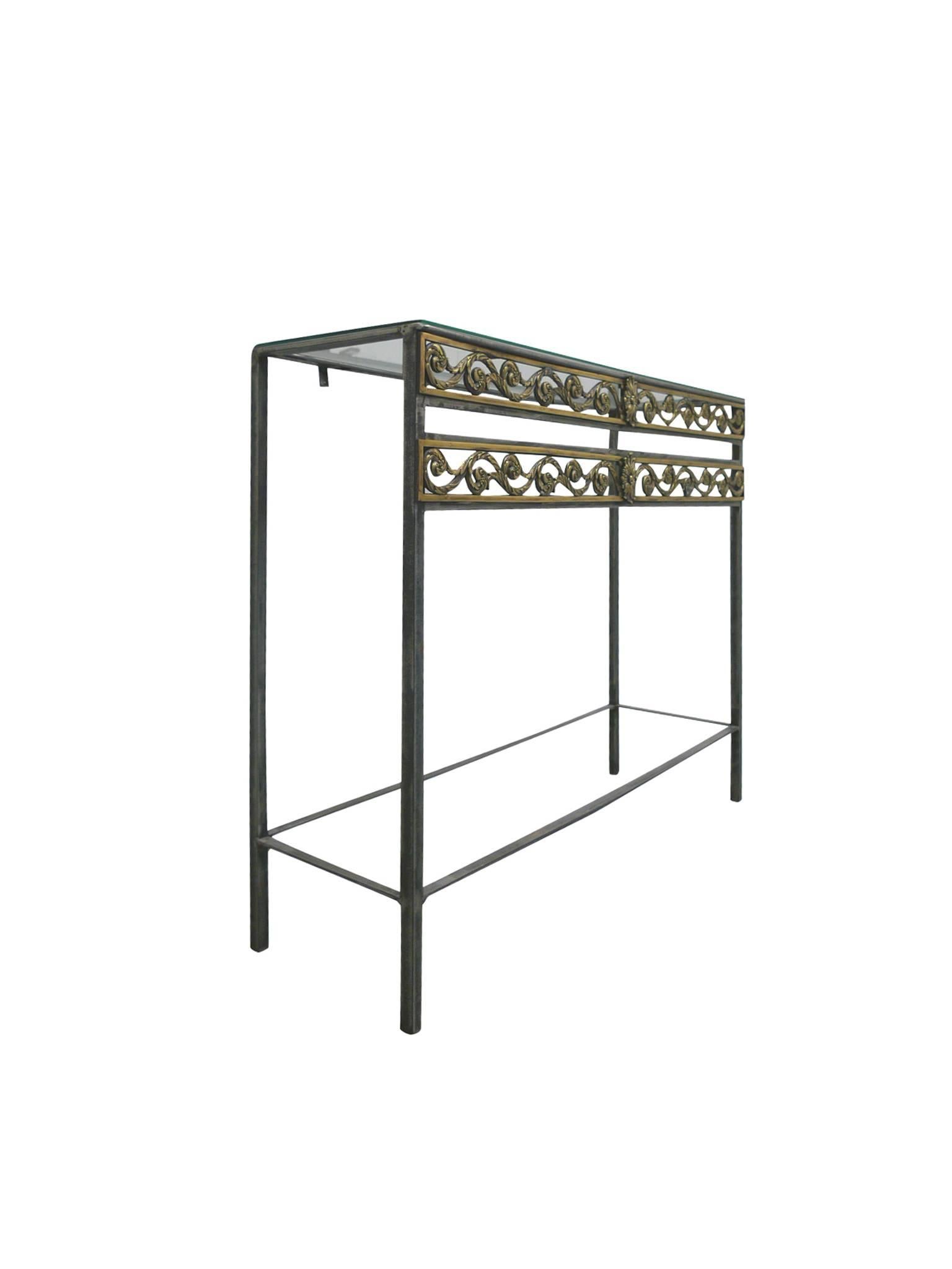This Oscar Bach style console table is comprised of a polished steel frame with decorative brass metalwork and a 1/4-inch thick transparent glass top. The openwork structure of the console creates airiness and transparency. It's a minimalist design