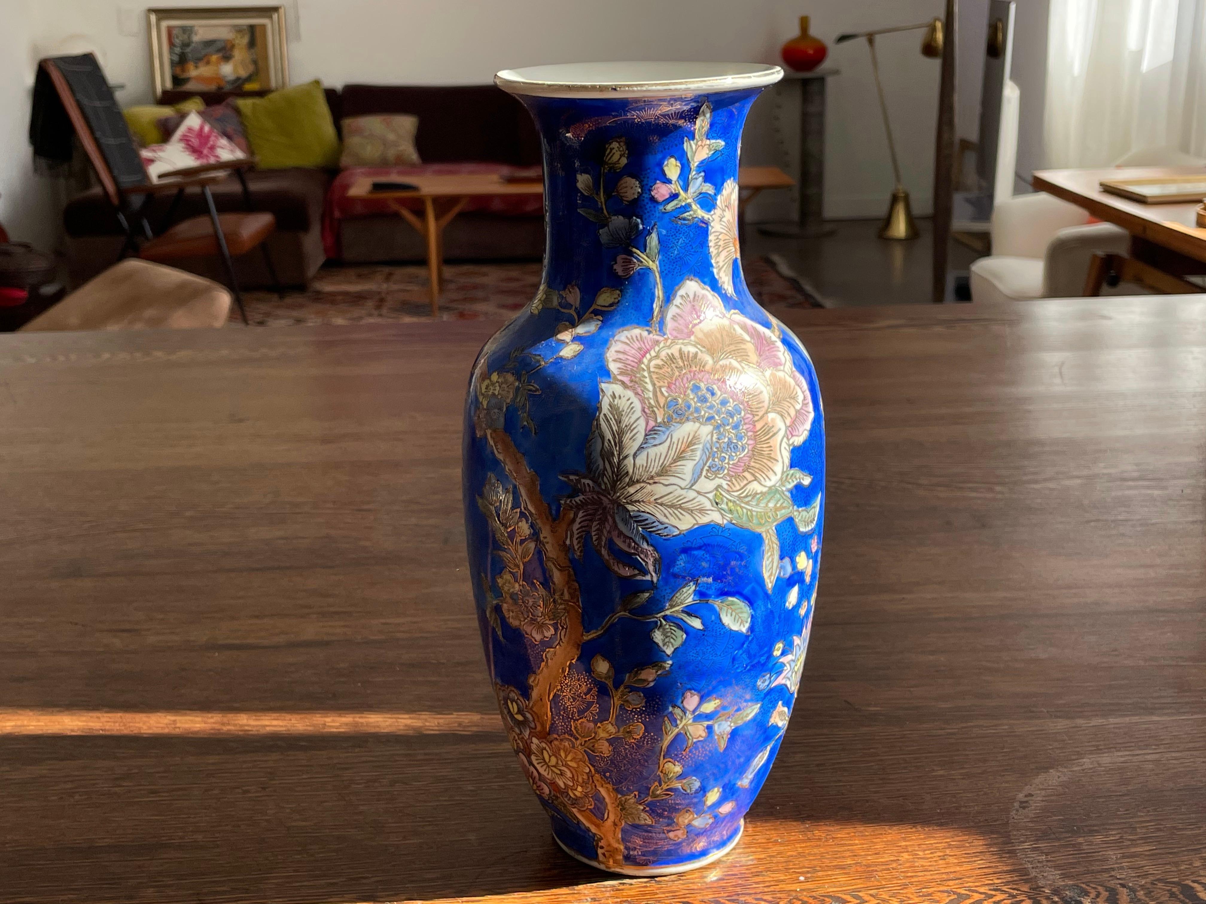 Un vase en porcelaine chinoise vintage, probablement des années 1960, en émail bleu décoré de belles fleurs et de délicats détails peints à la main en or. 
Signé.
  
Nous sommes un espace d'exposition et une destination en ligne créés par le