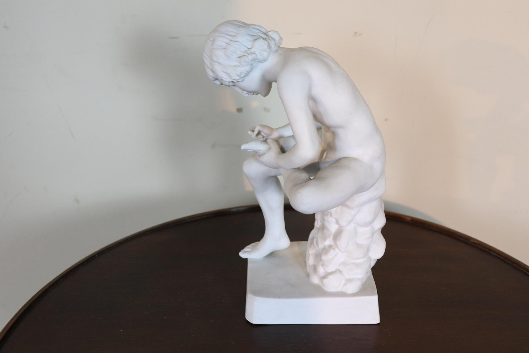 Refined sculpture in porcelain young boy sitting trying to remove a thorn from his foot. Figure of clear classic taste. Mark at the base.
