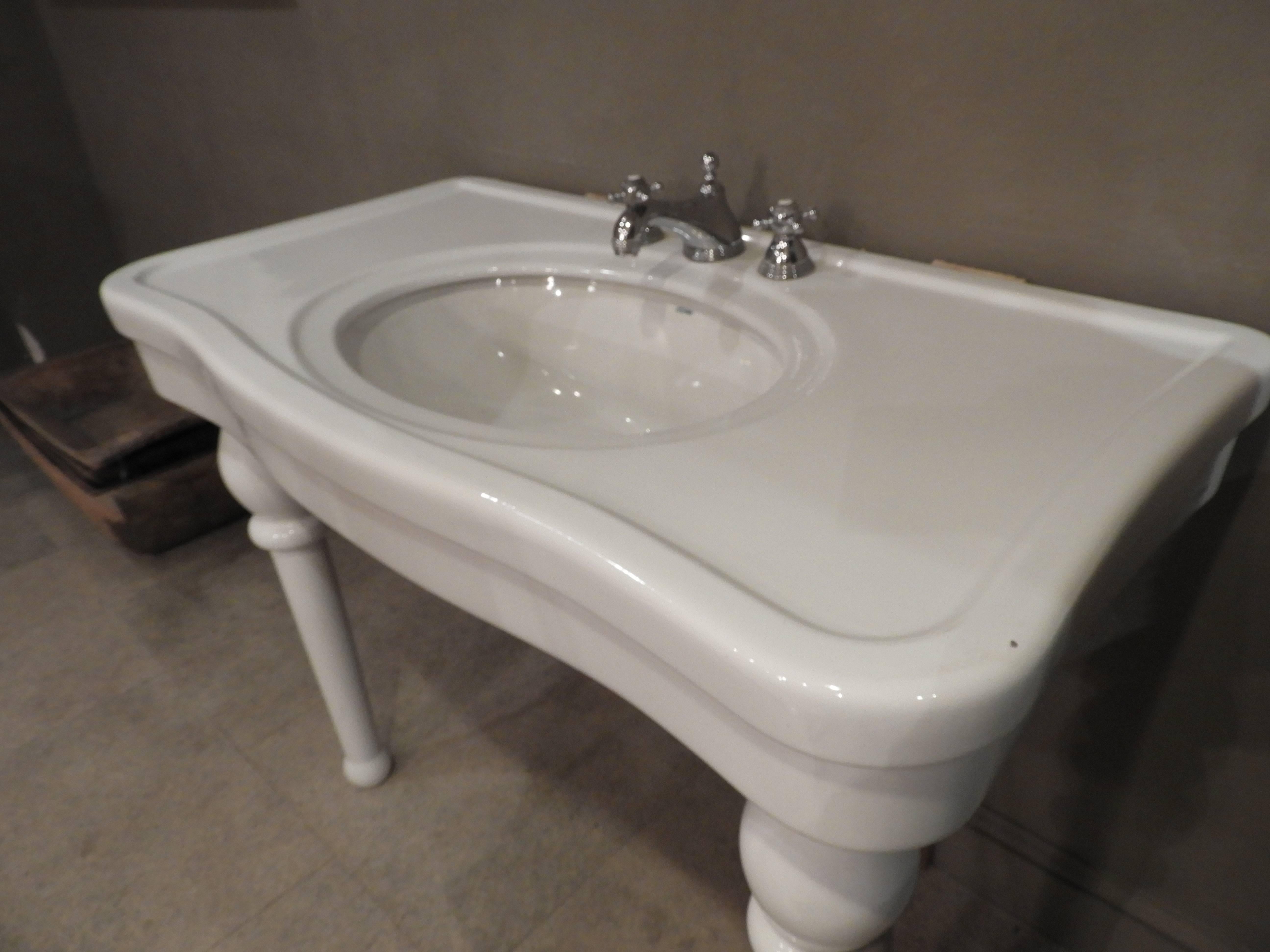 20th century porcelain sink with front legs and taps.