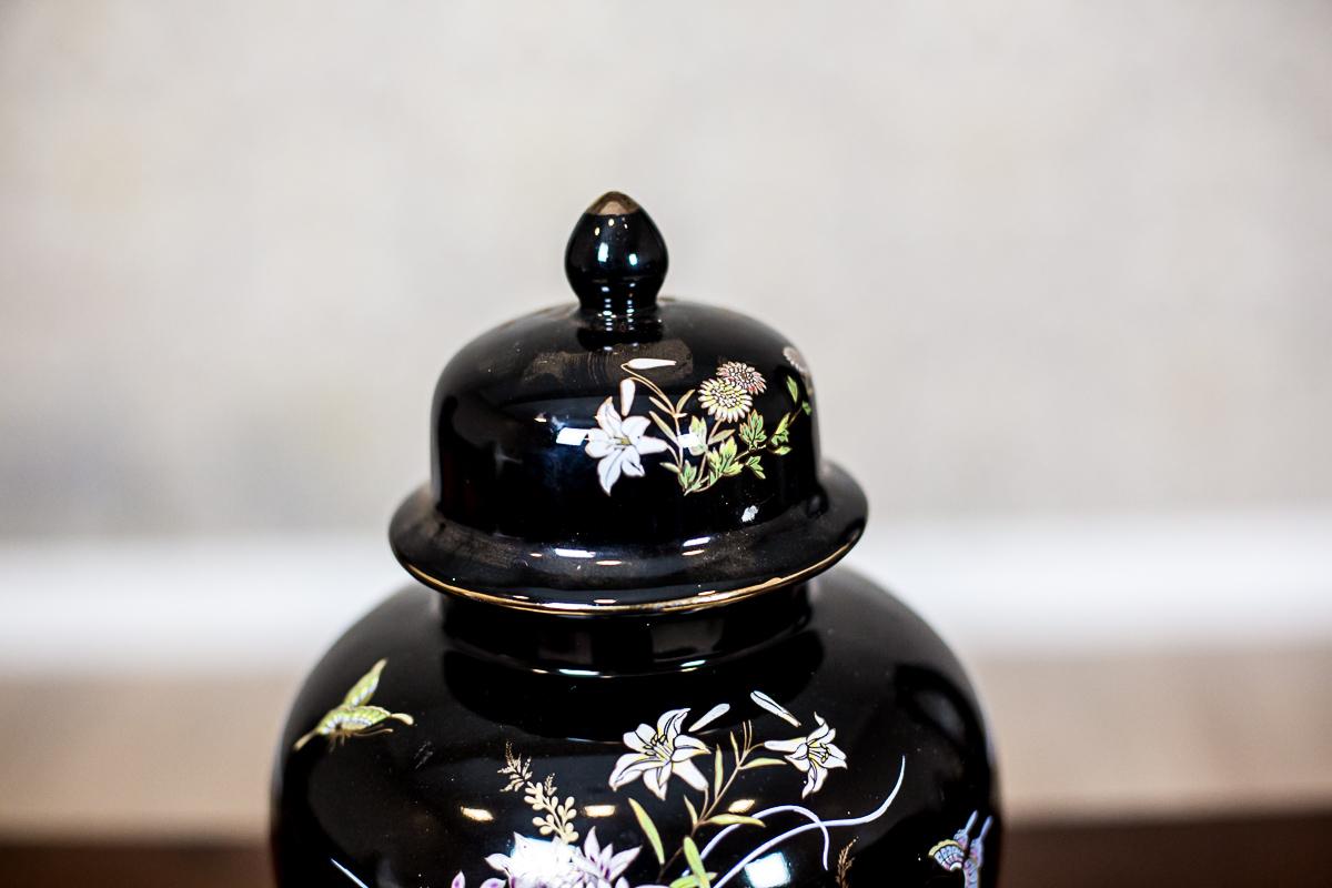 We present you this black vase with a multi-colored vegetative pattern on one side of the belly and the lid.
The plants have gilded frames, similarly to the stripes on the lid’s rim and at the base.

Height with lid: 26 cm. Hight without lid: