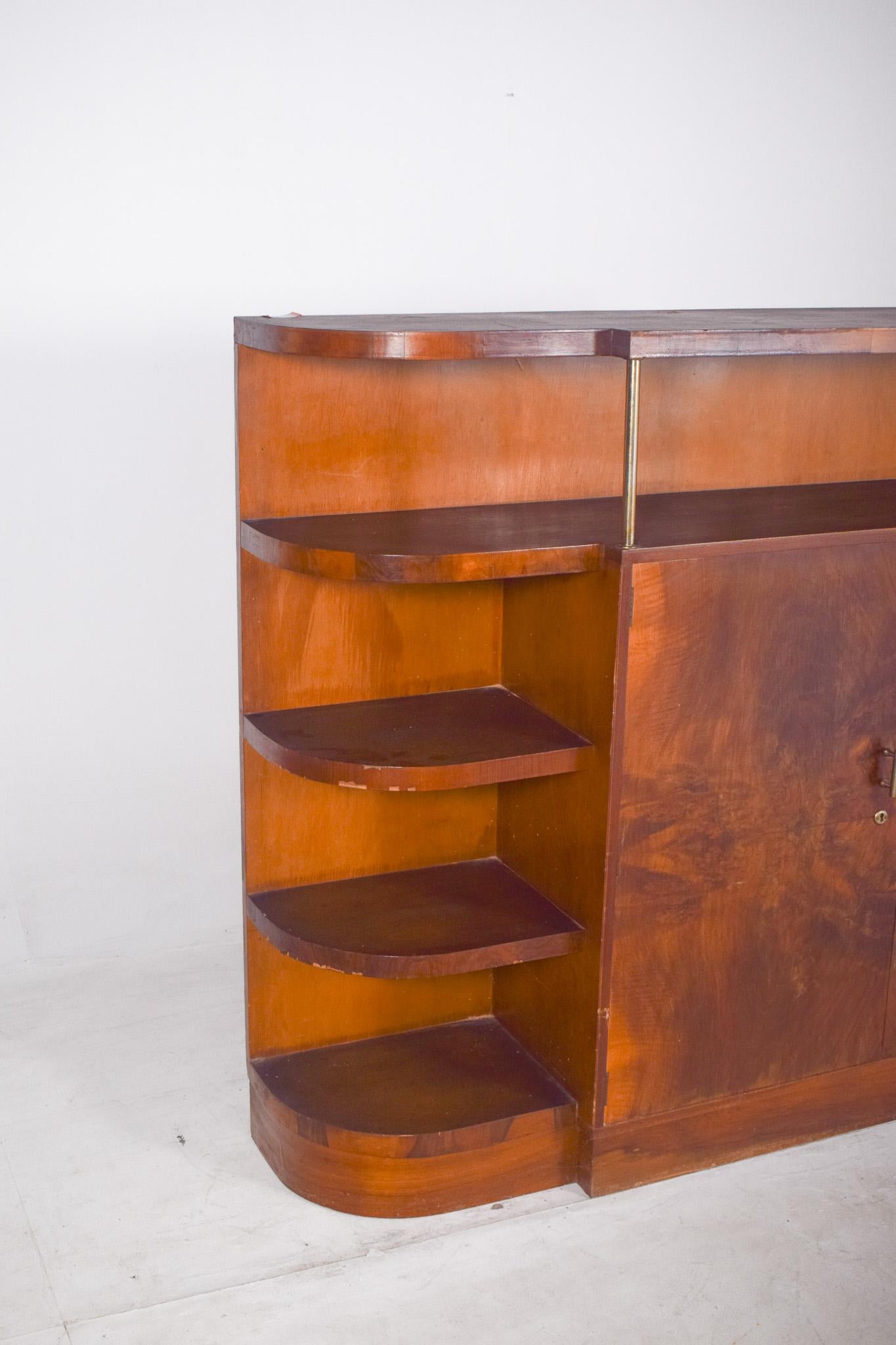 Libreria Art Deco. Il suo design elegante è caratterizzato da forme arrotondate, linee pulite ed equilibrio, che ne caratterizzano anche la funzionalità. Il pezzo si distingue per la sua asimmetria visivamente interessante: a sinistra, tre ripiani