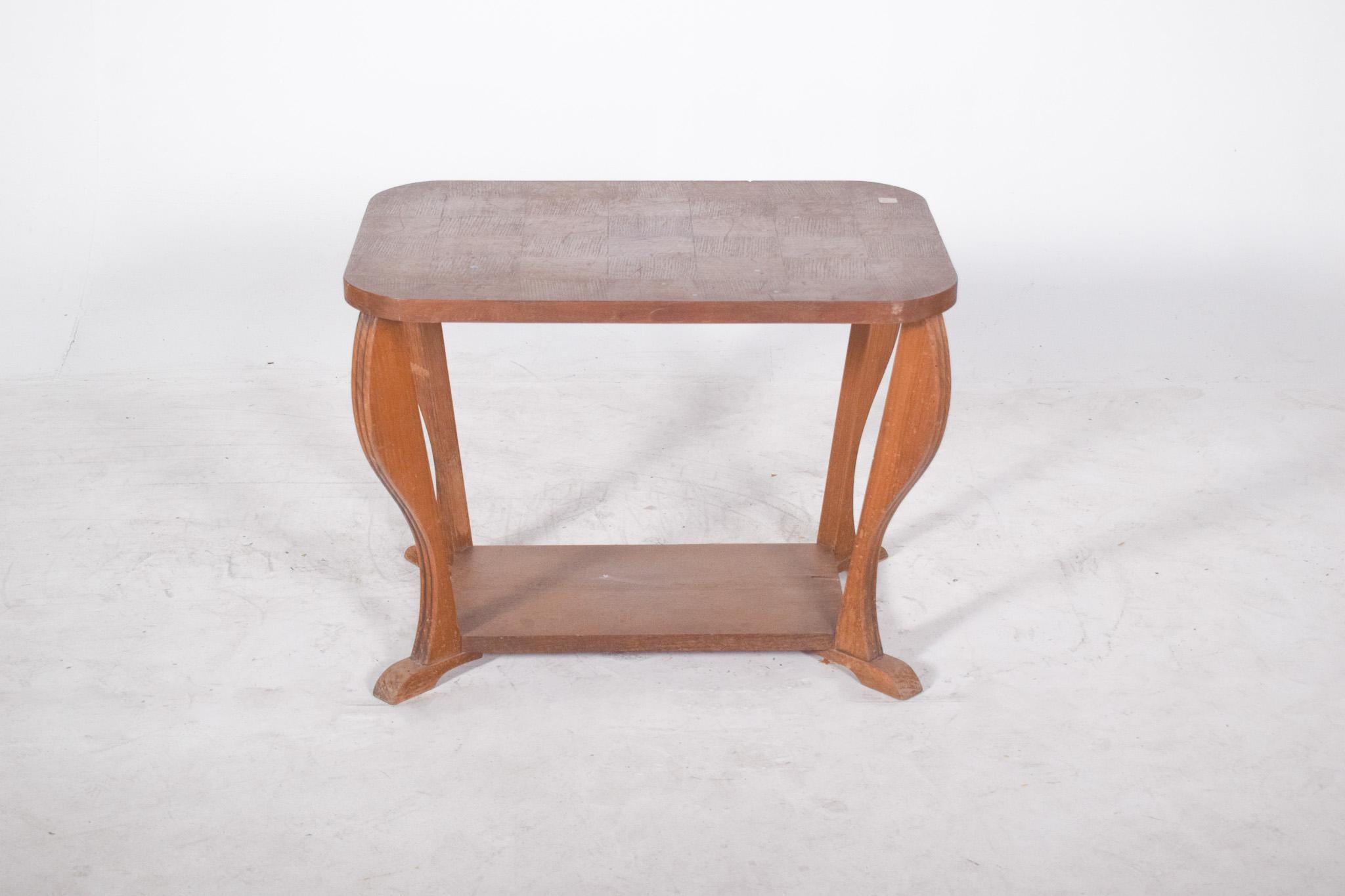 Art Deco coffee table. Marked by curved lines and softly sculpted legs, it has a rectangular top with rounded corners supported by four arched legs, connected by a lower plane that acts as a support shelf.
The structure presents a combination of