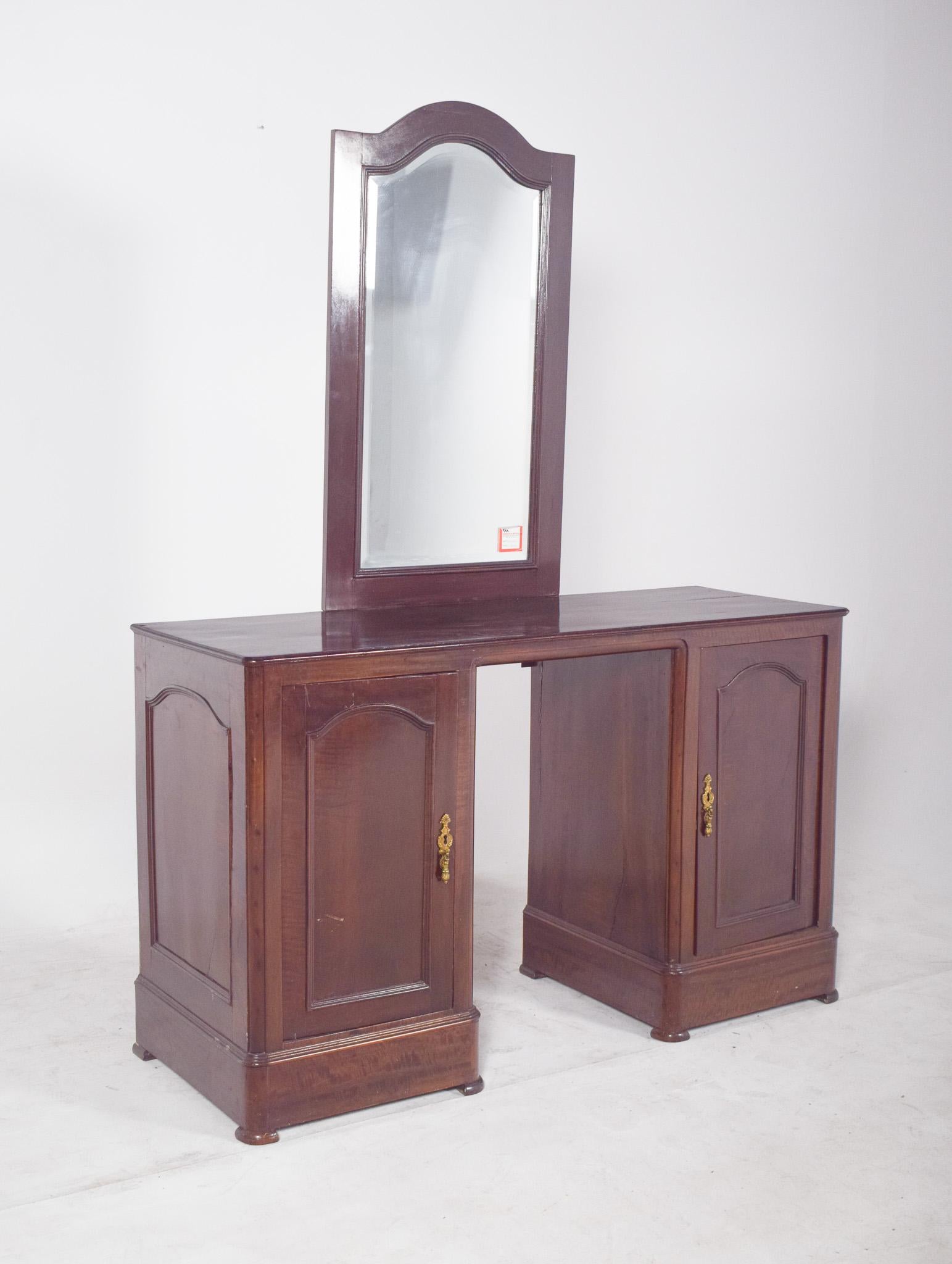 Dressing table with mirror. Two lower doors with decorated metal handles provide discreet and functional storage space, while the central opening suggests use as a dressing table and personal grooming area.
The mirror with a curved top frame softens