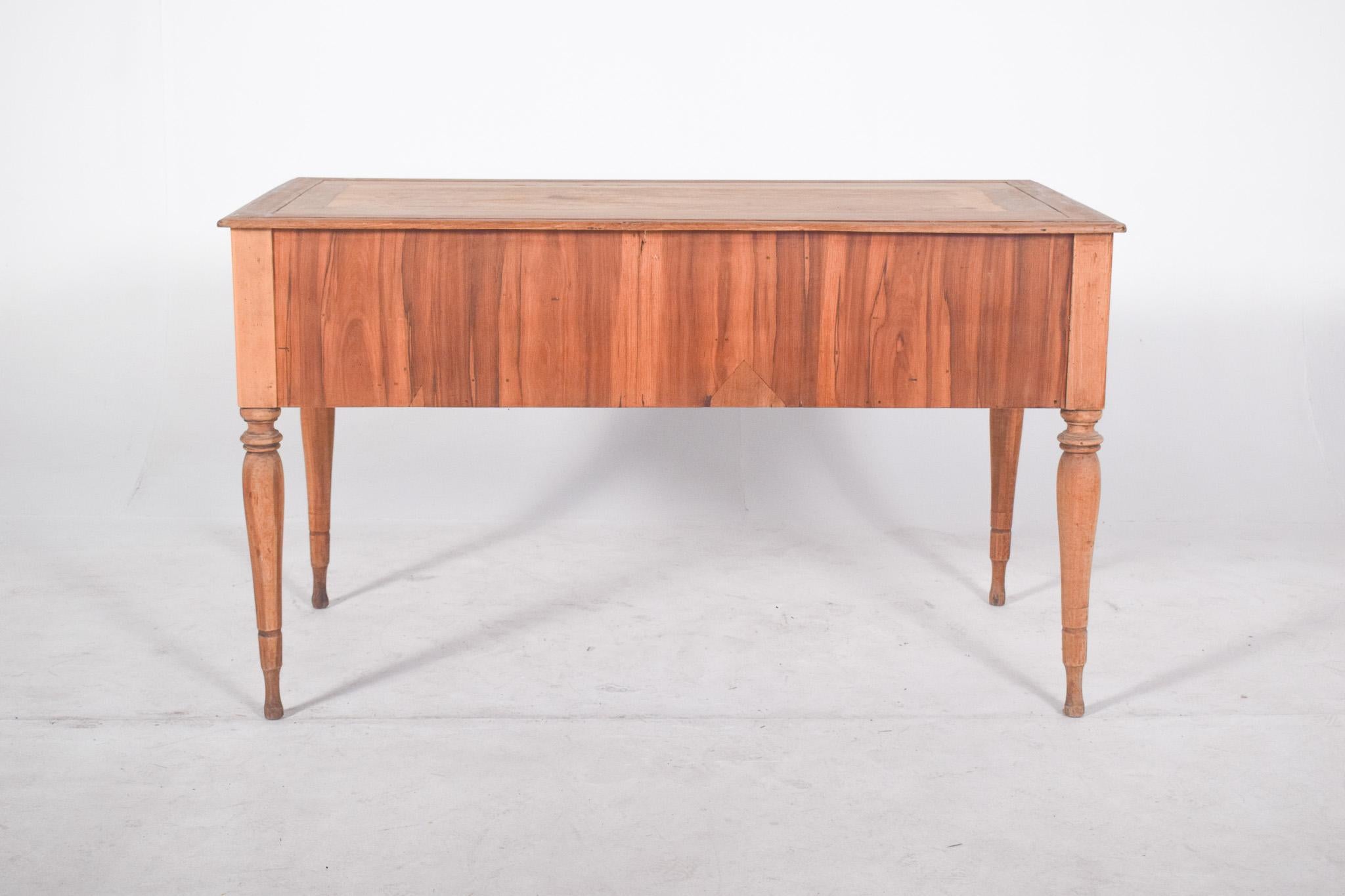Romantic desk with four drawers. With an elegant and symmetrical design, the piece is made of light wood with visible natural veins, giving it a rustic and sophisticated look at the same time. The desk has four turned legs, which add a touch of