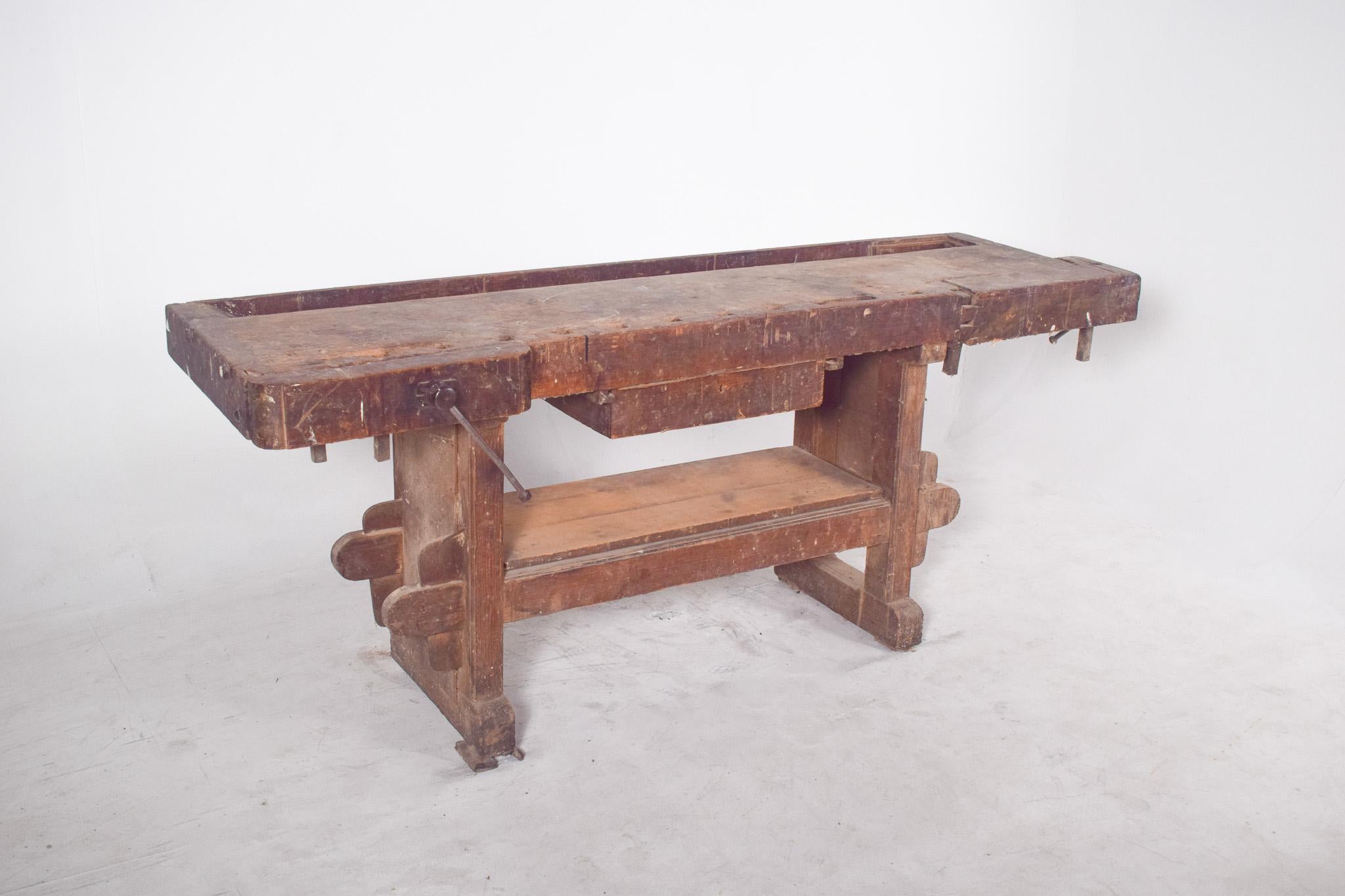 Cabinetmaker's work bench. This solid wood carpenter's bench carries the history of the craft in every mark and wear visible on its surface. With its robust structure and long-used features, it is designed to withstand decades of intense use in