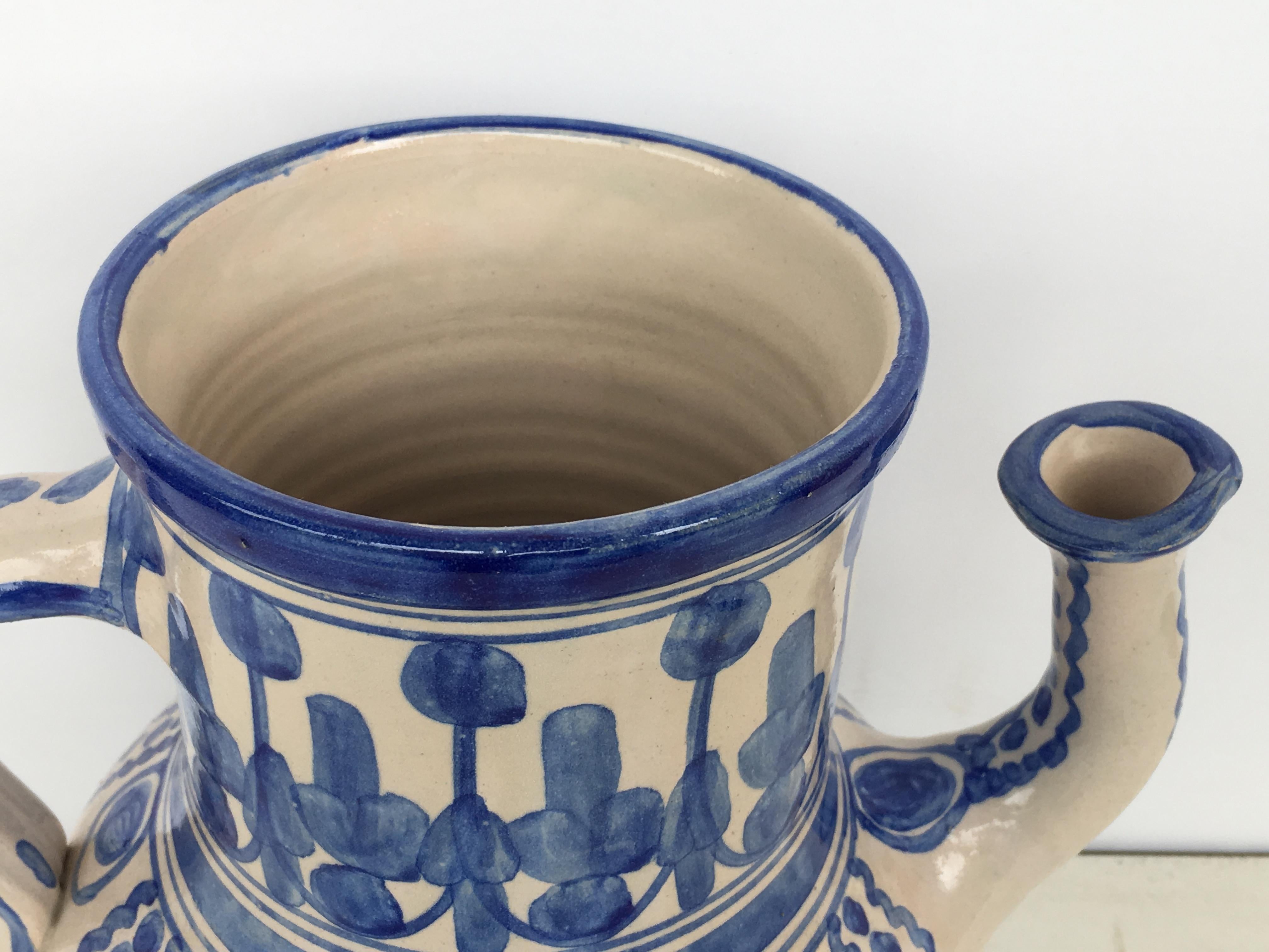 A striking Spanish glazed earthenware two-handled blue and white painted pitcher, the body underglaze ornamental blue decorated .

Talavera de la Reina pottery is a craft made in Talavera de la Reina, Toledo (Spain). Dishes, jars and other objects