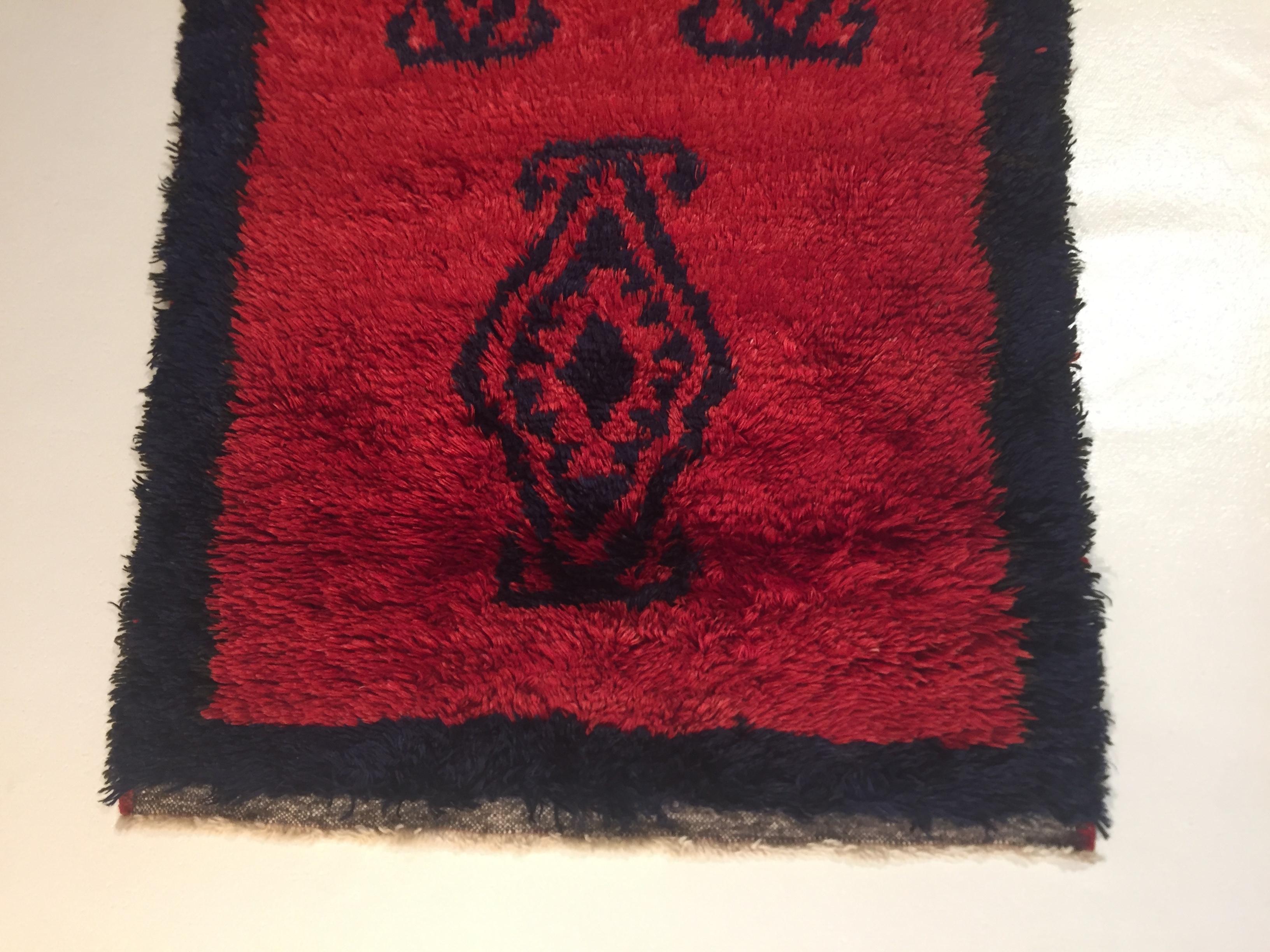 Tulu avec un fond d'un beau rouge cochenille, décoré de polygones de forme irrégulière en noir.
Les tapis Tulu sont des tapis turcs à poils hauts et irréguliers, avec des décorations très simples et des couleurs vives, principalement utilisés comme