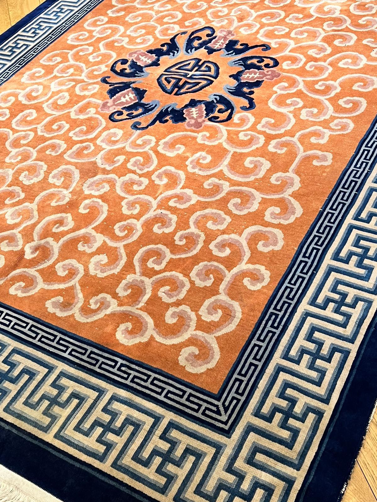 Red field Peking rug with white clouds and borders with continuous patterns in blue and white symbolise good luck and prosperity. A typical product of Chinese craftsmanship inspired by porcelain of the ancient Chinese dynasty.
