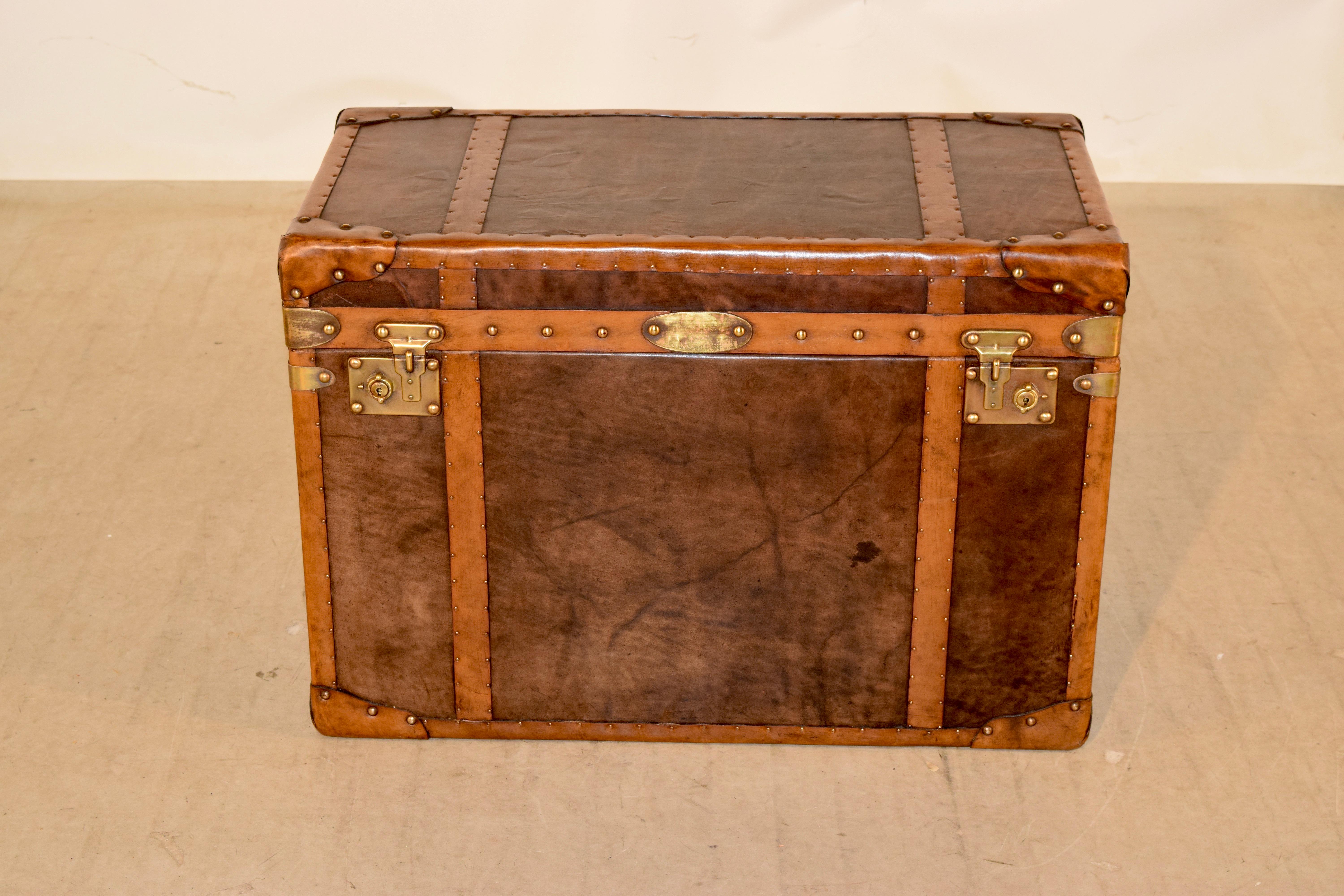 Early 20th century English steamer trunk which has been completely refurbished. The exterior features contrasting colors of leather with brass nail decoration, along with brass hardware and new interior lining.