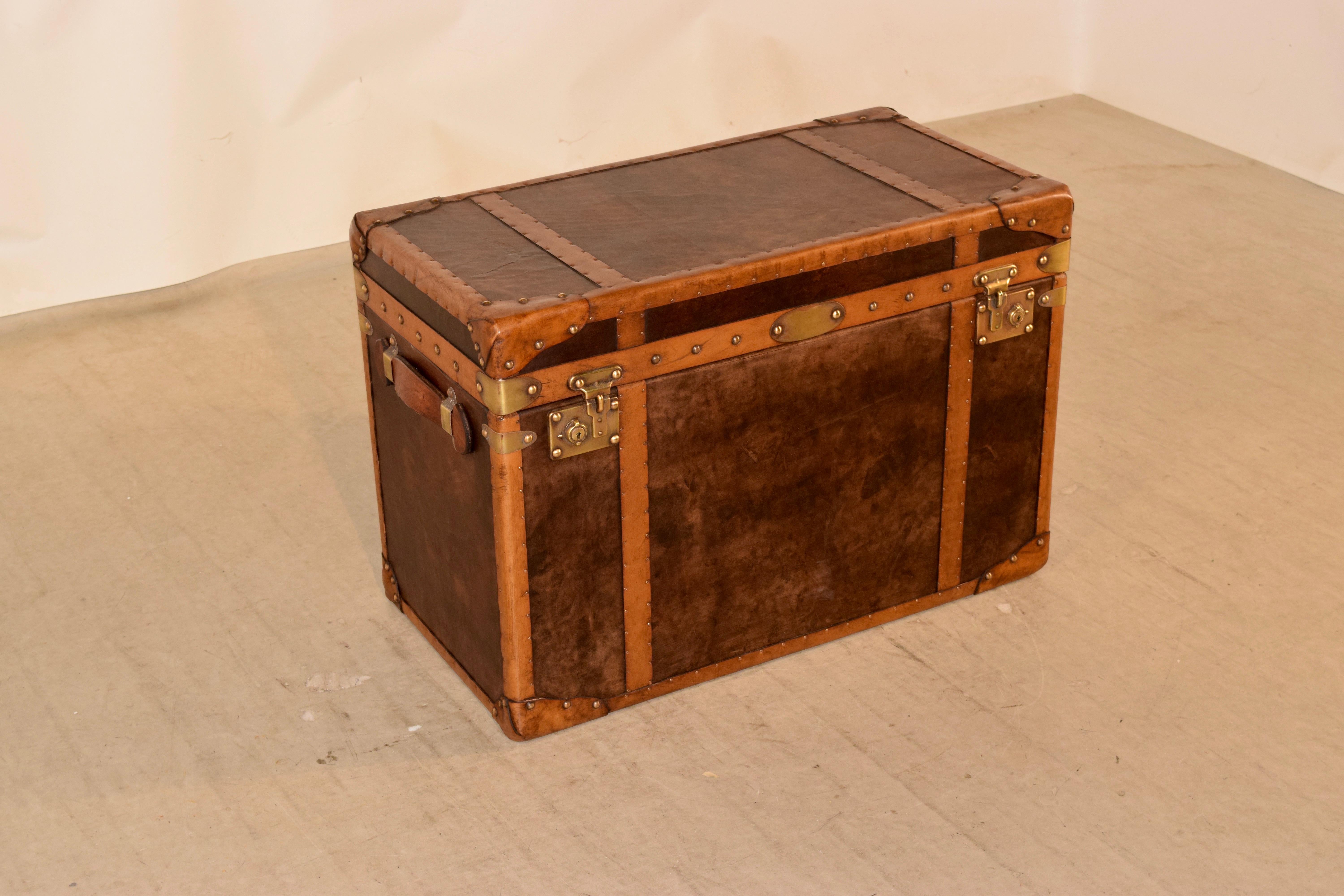 Early 20th century English steamer trunk which has been completely refurbished. The exterior features contrasting colors of leather with brass nail decoration, along with brass hardware and new interior lining.