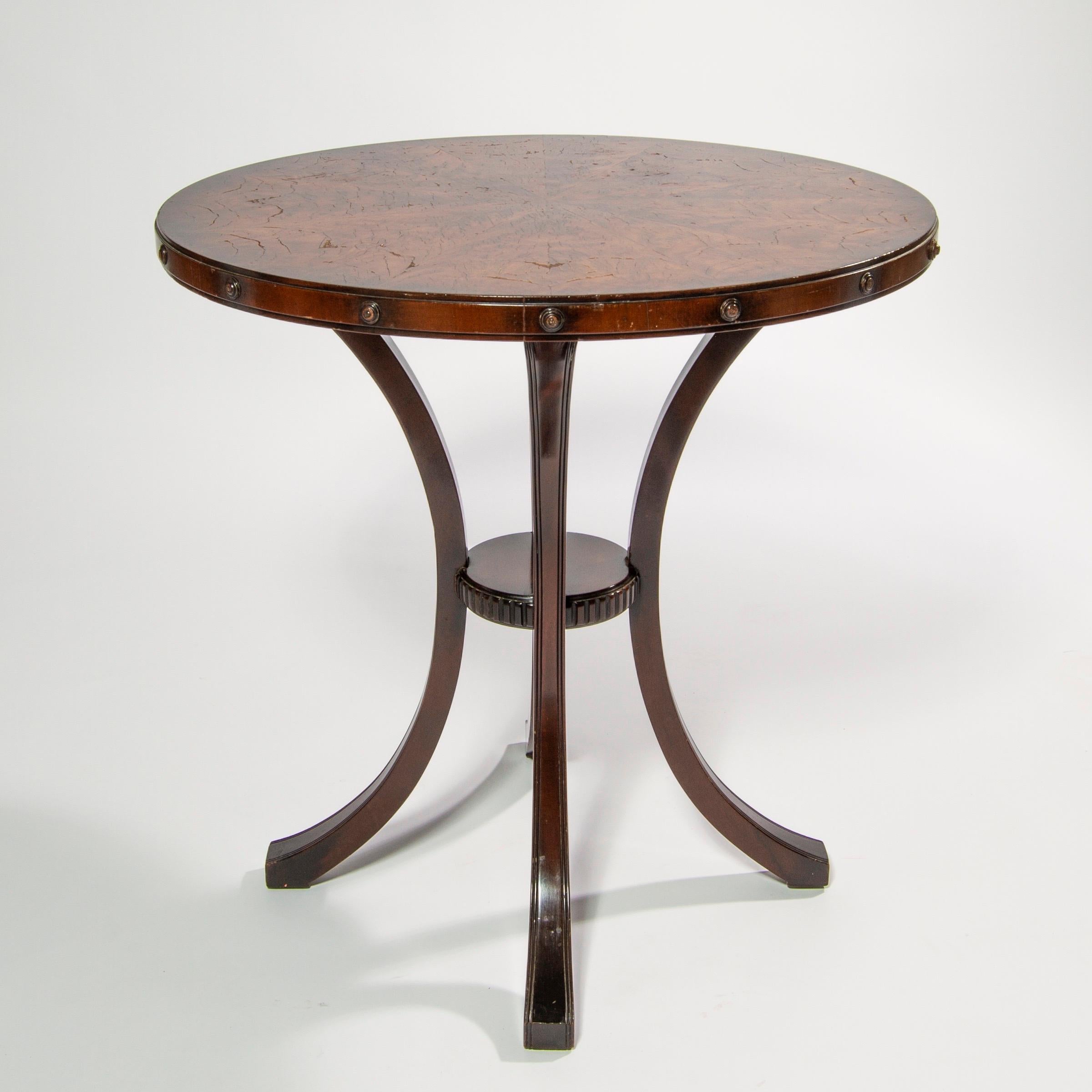 Round center, side, or end table rendered in walnut with inlay marquetry top and shelf, carved studded detail around top edge

14