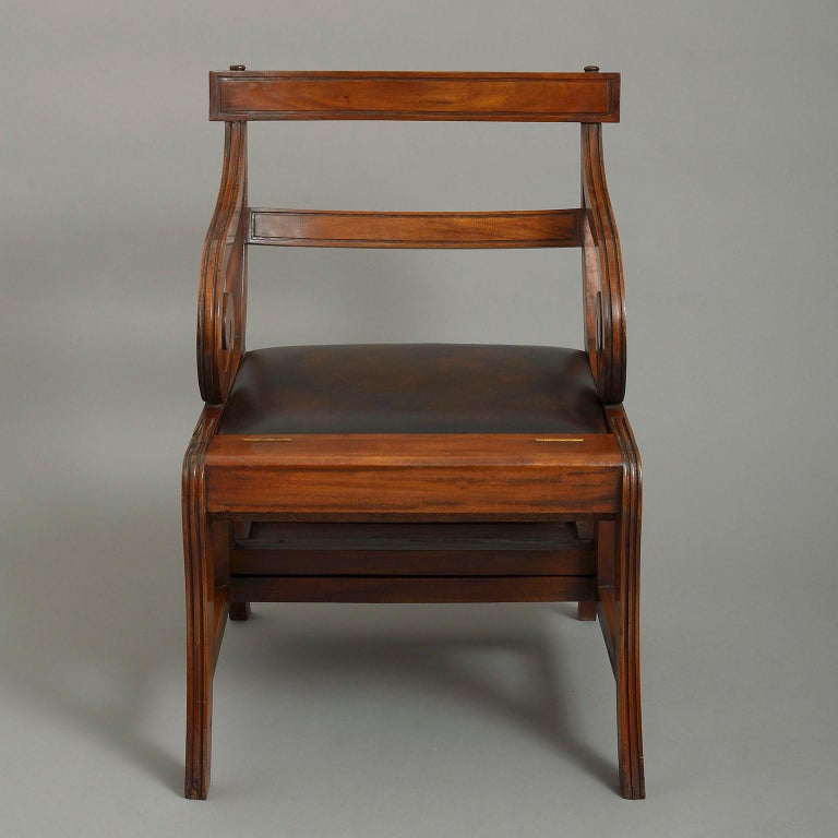 A 20th century Regency style large metamorphic library chair with scroll arms and sabre legs, converting to library steps.