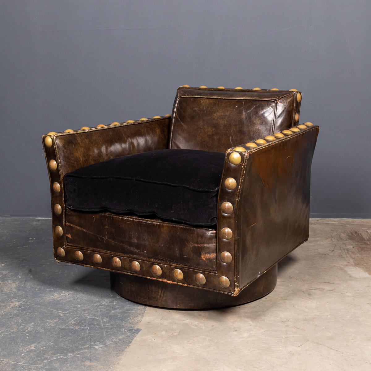 Stylish revolving club chair with its original leather upholstery with stunning over sized brass studs The seat cushion has been reupholstered in black velvet. Made by Baker, an American company that has been making fine furniture since 1890's.