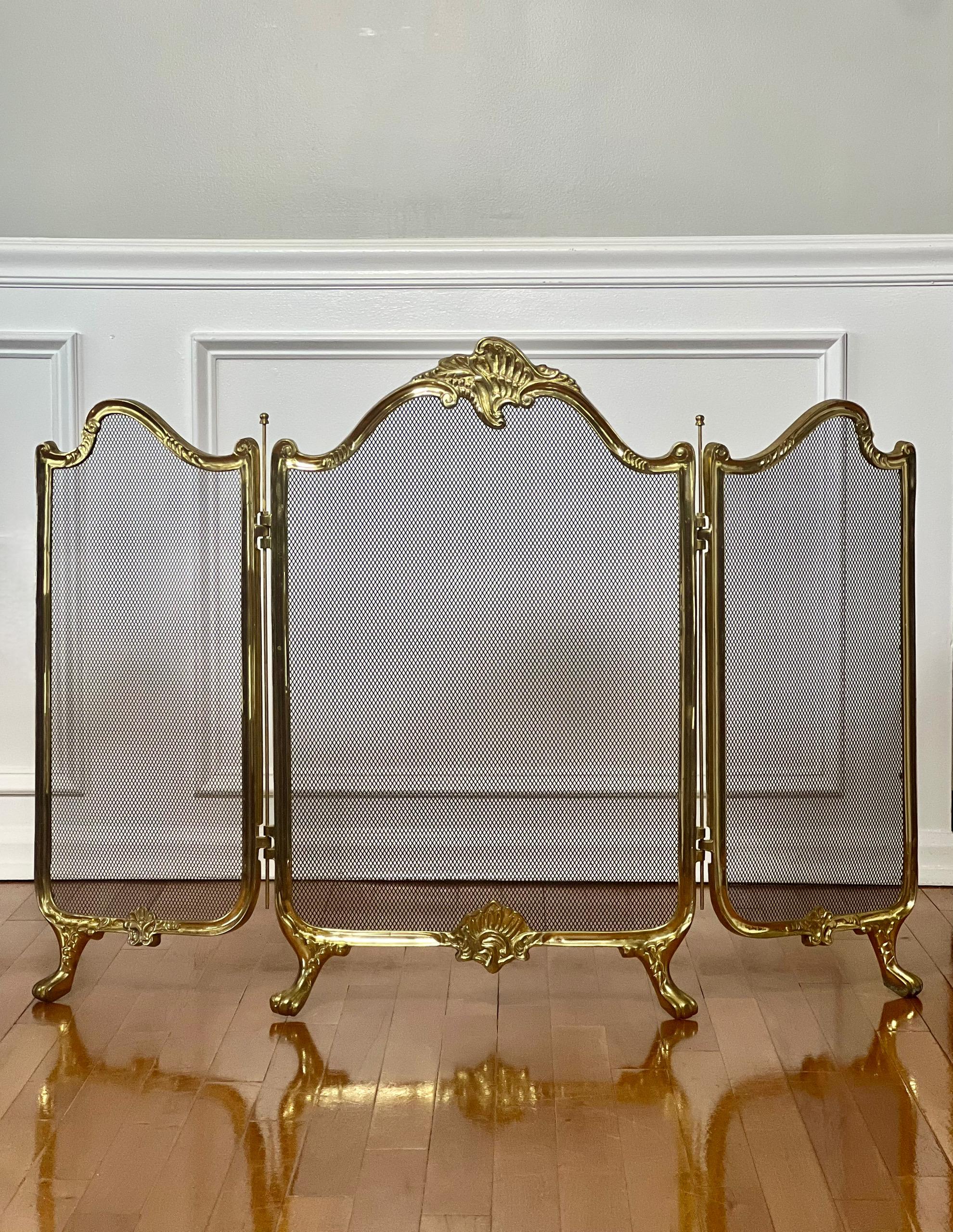 Vintage Rococo style brass three-panel fireplace screen, circa mid 20th century. A nicely shaped, solid cast brass design features foliate motifs, paw feet and prominent hinge bars. The larger center panel (18