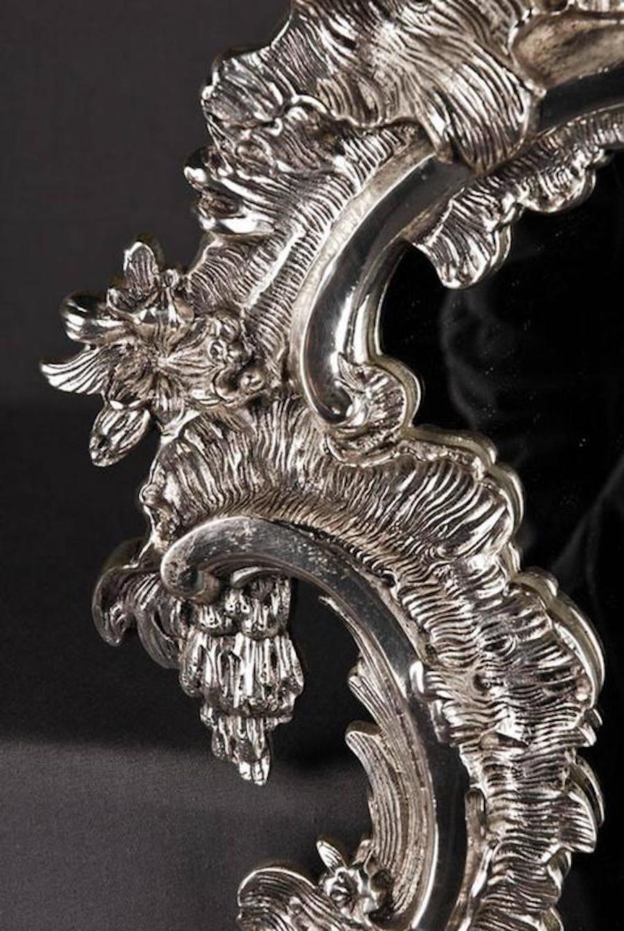 Délicat miroir mural de style rococo.
Bronze, finement gravé et doré à l'argent. Cadre de miroir formé en Rocaille. 

(A&M-27-Bas)